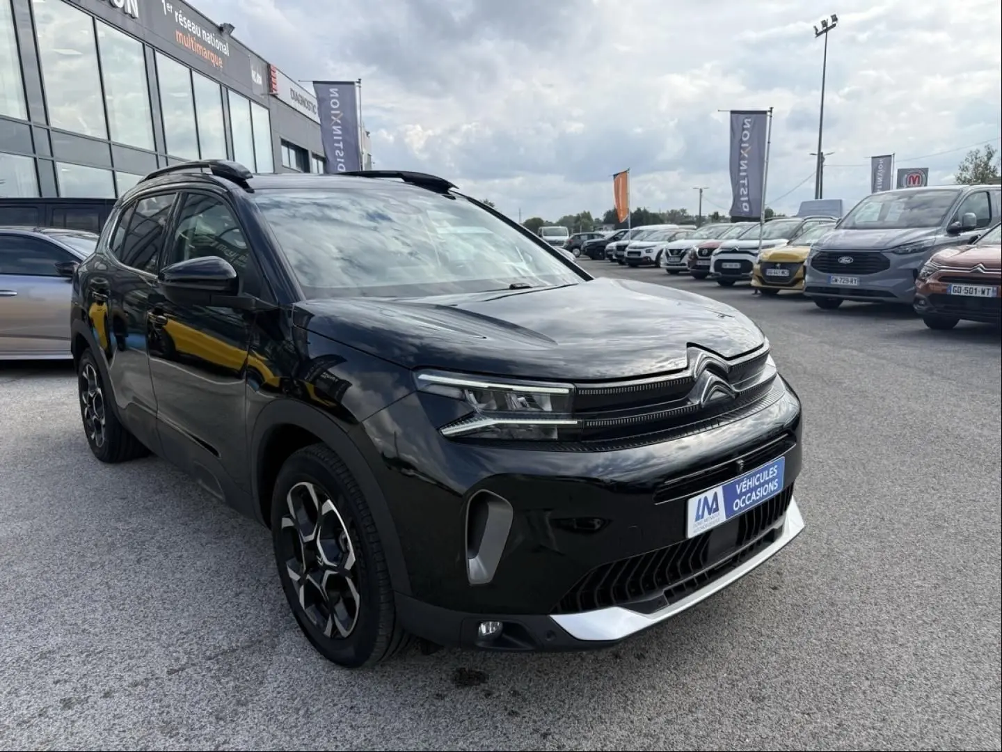 Citroën C5 Aircross noir métal en 3/4 avant droit, avec jantes distinctives et calandre moderne visible.
