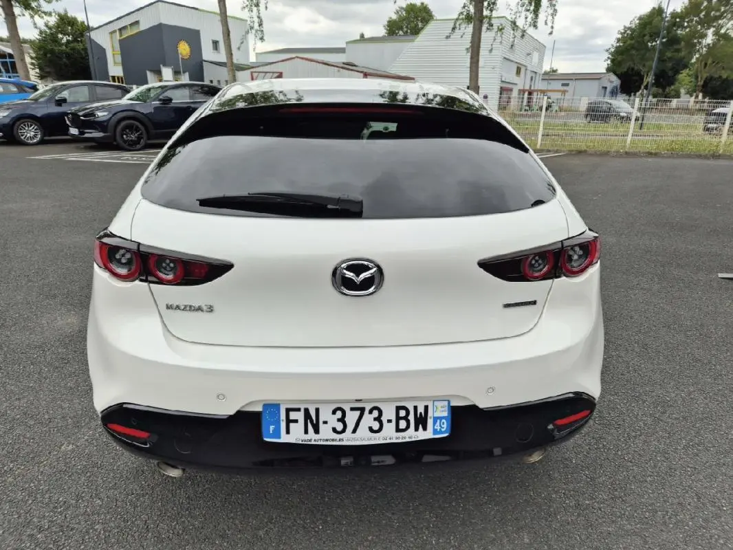 Vue arrière d'une Mazda3 blanche de 2020 avec feux arrière ronds et plaque d'immatriculation française visible