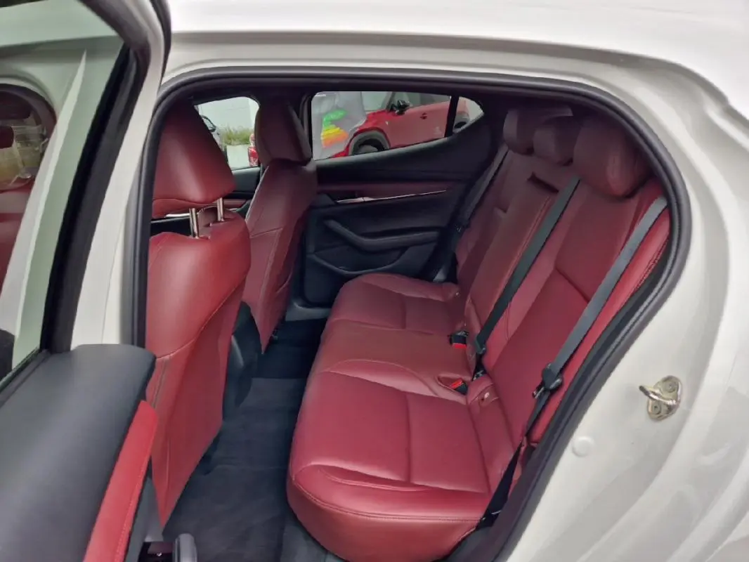 Vue intérieure côté droit montrant les sièges arrière en cuir rouge d'une Mazda3 blanche de 2020.