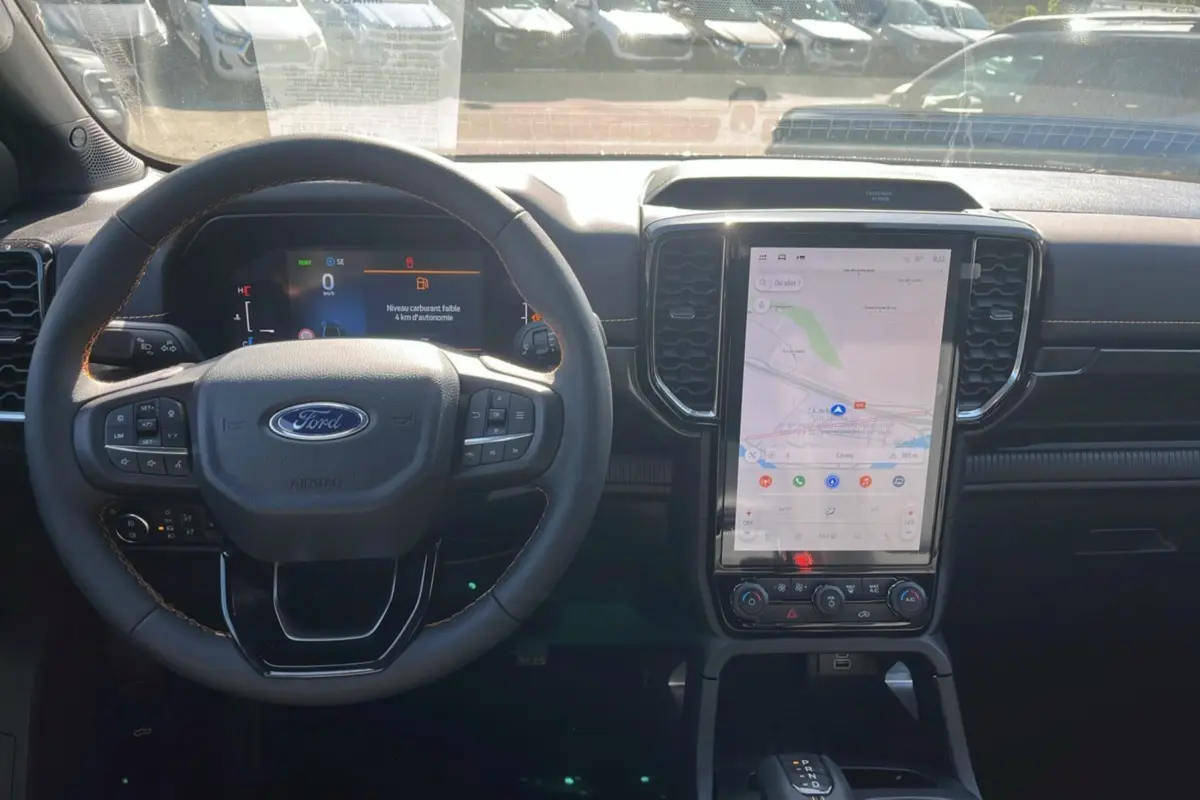Vue intérieure du tableau de bord du Ford Ranger PHEV 281 Wildtrak, avec volant cuir et écran tactile central vertical.