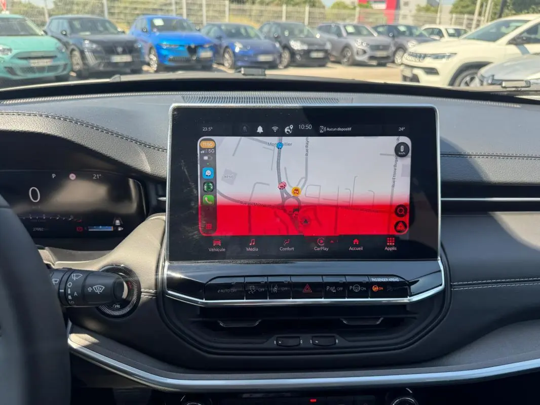 Vue intérieure centrée sur l'écran tactile du tableau de bord du Jeep Compass blanc 2025, avec commandes visibles.
