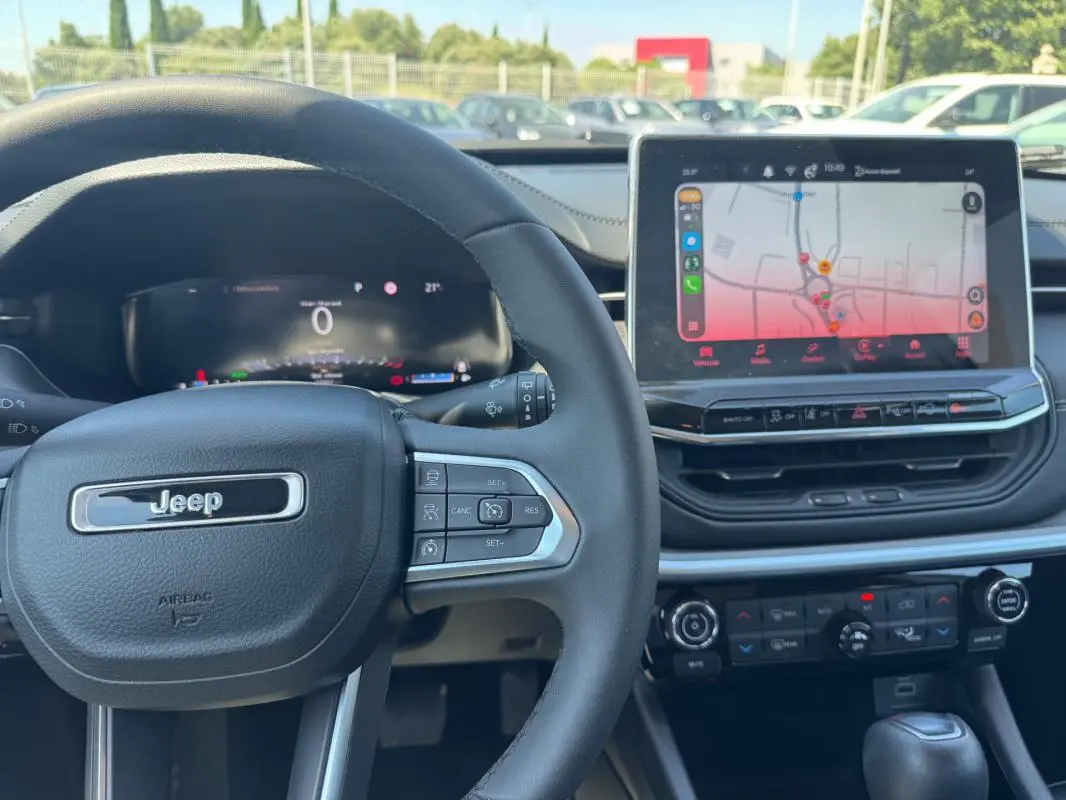 Vue intérieure centrée sur le volant Jeep et l’écran tactile du tableau de bord du Compass blanc 2025.