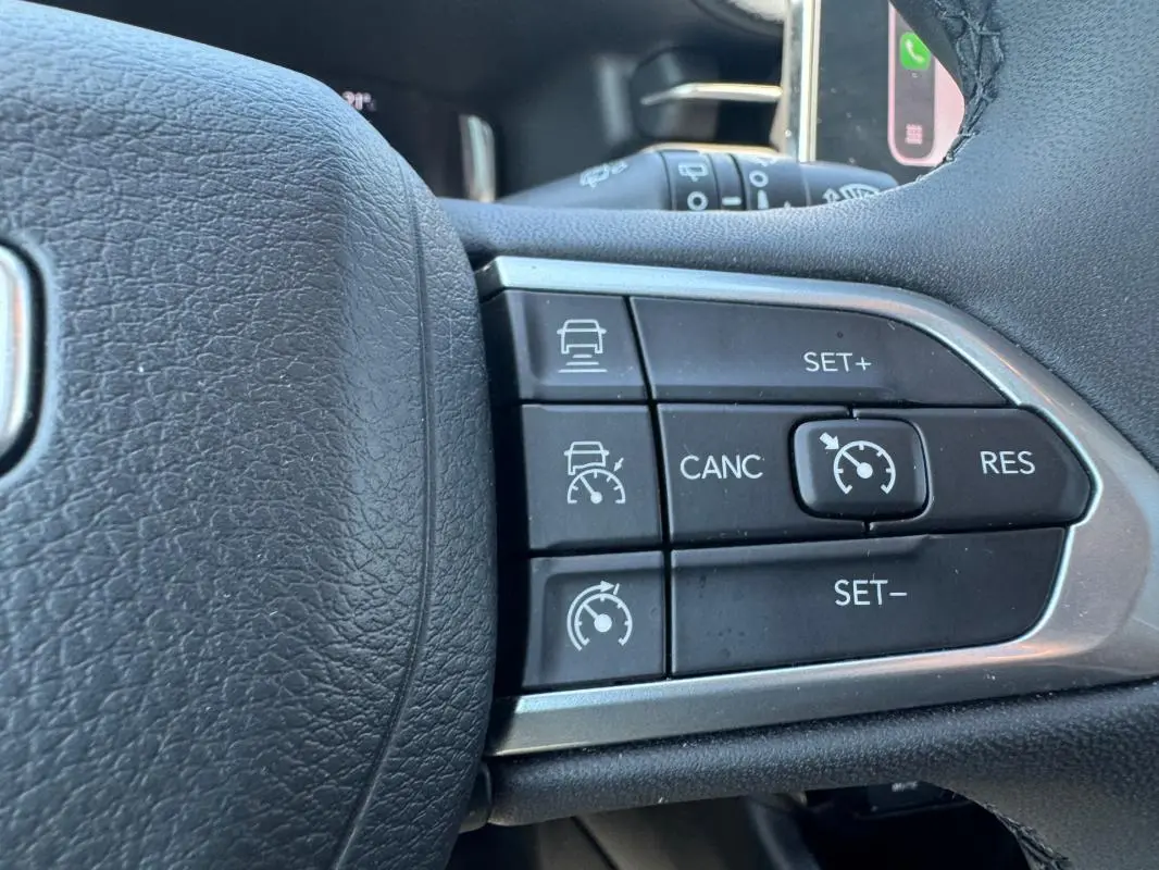Gros plan sur les commandes du régulateur de vitesse au volant d’un Jeep Compass blanc 2025.