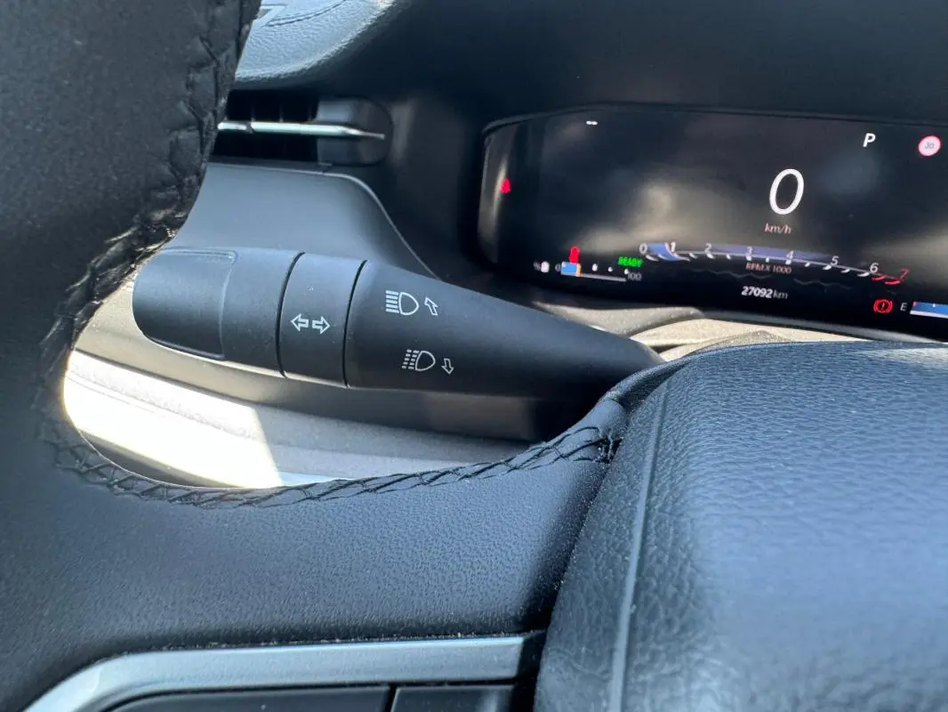 Gros plan sur la manette de clignotants et le tableau de bord numérique noir du Jeep Compass blanc 2025.
