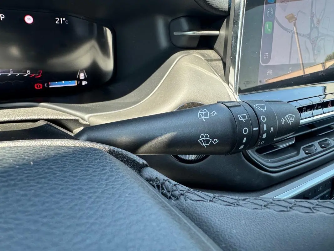 Gros plan sur la commande d’essuie-glace du tableau de bord noir du Jeep Compass blanc 2025, avec écran tactile visible.