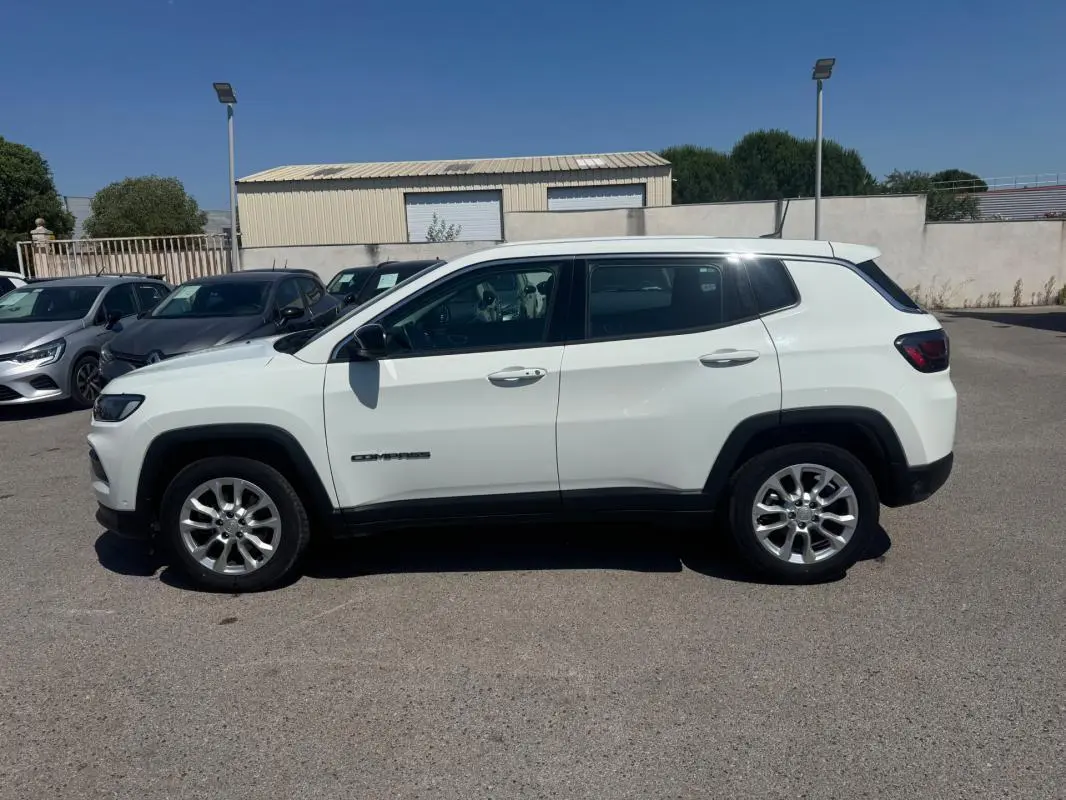 Vue de profil côté gauche d'un Jeep Compass blanc 2025 avec jantes alliage et vitres teintées.