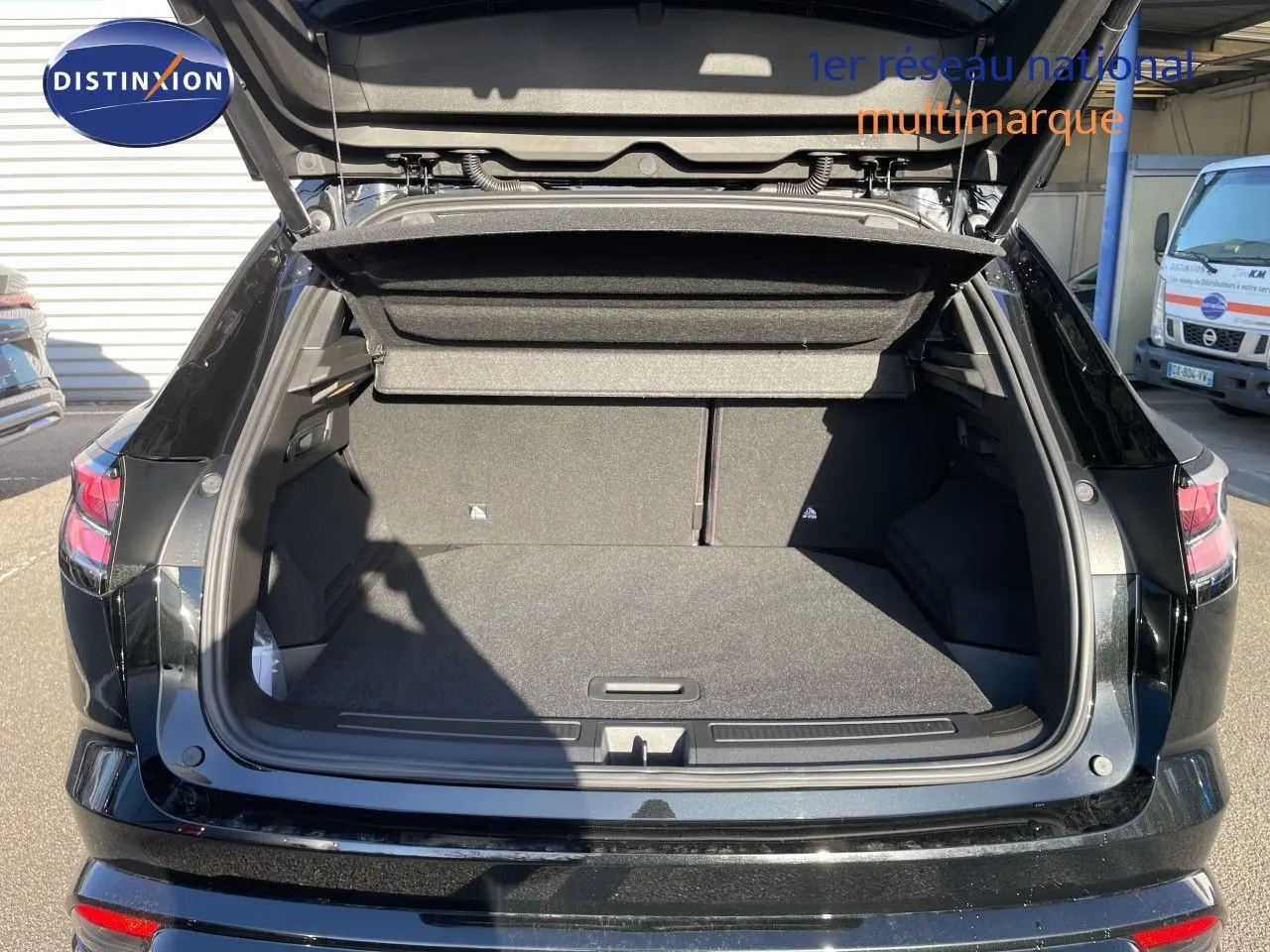 Coffre ouvert vu de l'arrière d'un Renault Austral E-Tech Full Hybrid noir étoile métal, montrant l'espace de chargement vide.