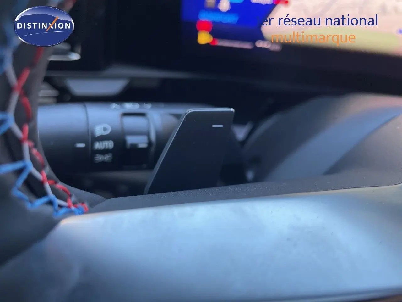 Gros plan sur la palette de changement de vitesse derrière le volant cuir noir avec surpiqûres rouges du Renault Austral noir étoile métal.