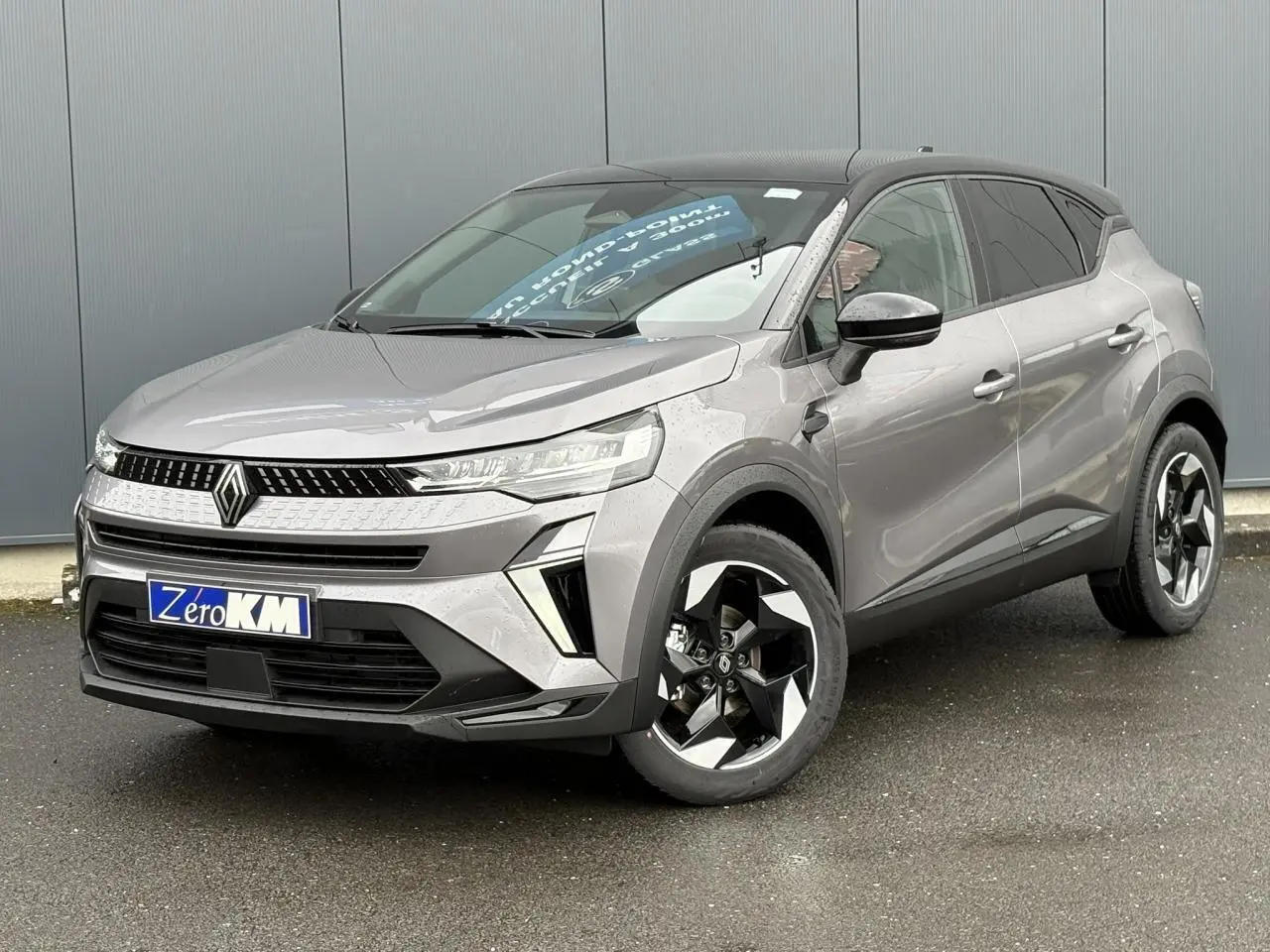 Renault Captur Gris Cassiopée en 3/4 avant droit, toit noir étoilé et jantes aluminium noires distinctives.