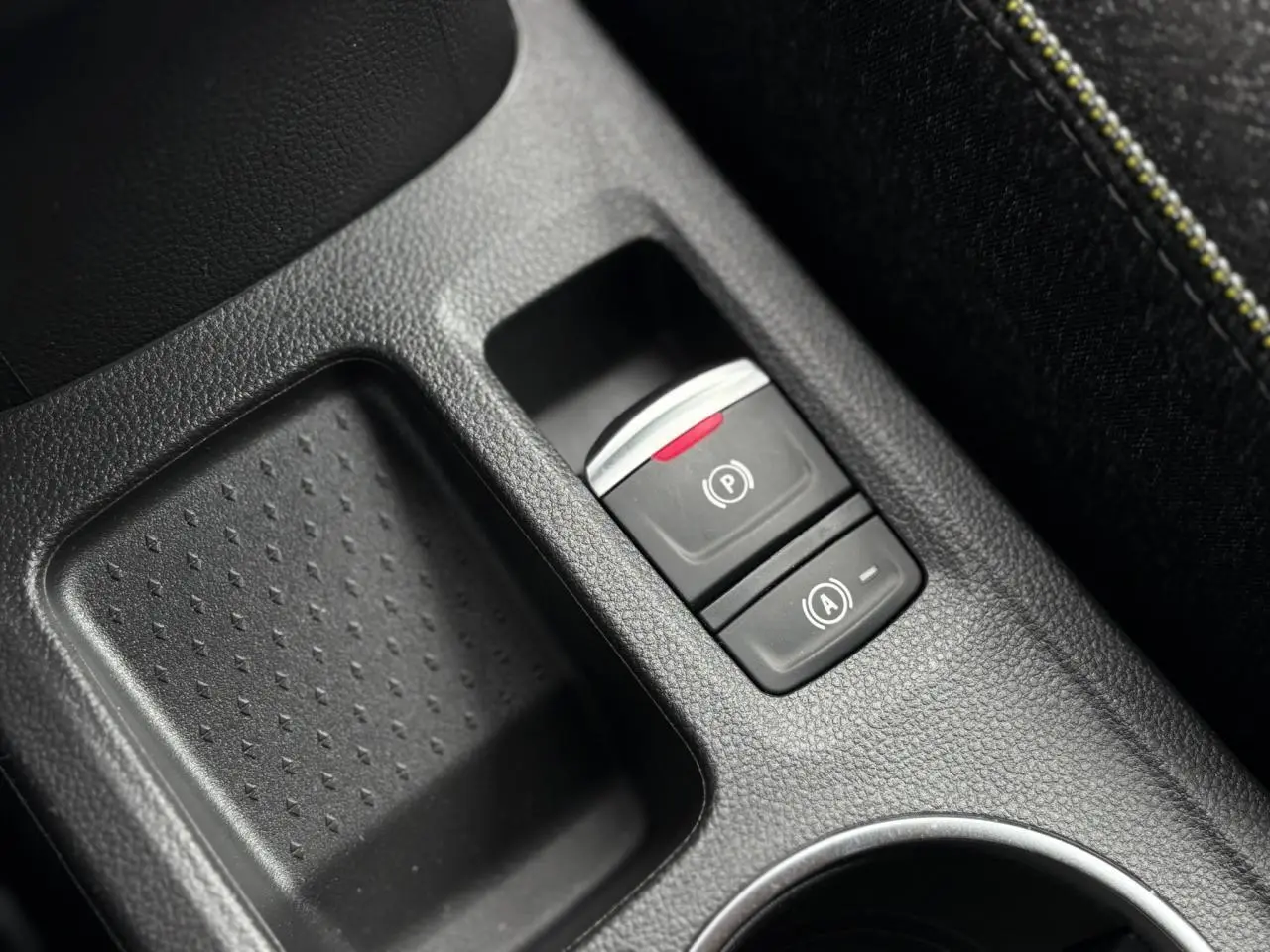 Gros plan sur la console centrale noire du Renault Captur 2025 avec frein de parking électrique et bouton Auto-Hold.