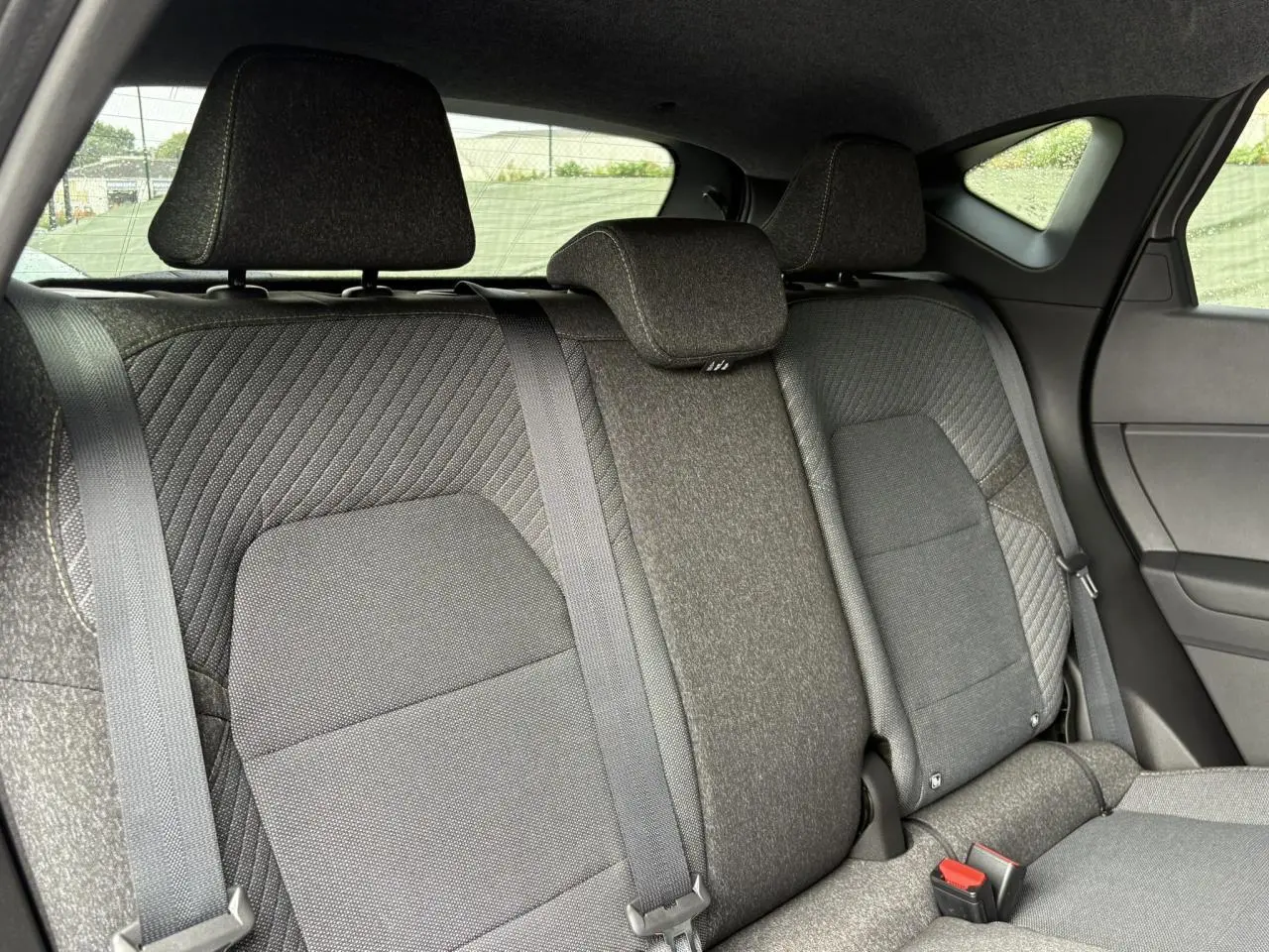 Vue intérieure sur la banquette arrière gris foncé du Renault Captur 2025 avec appuis-tête et ceintures de sécurité visibles.