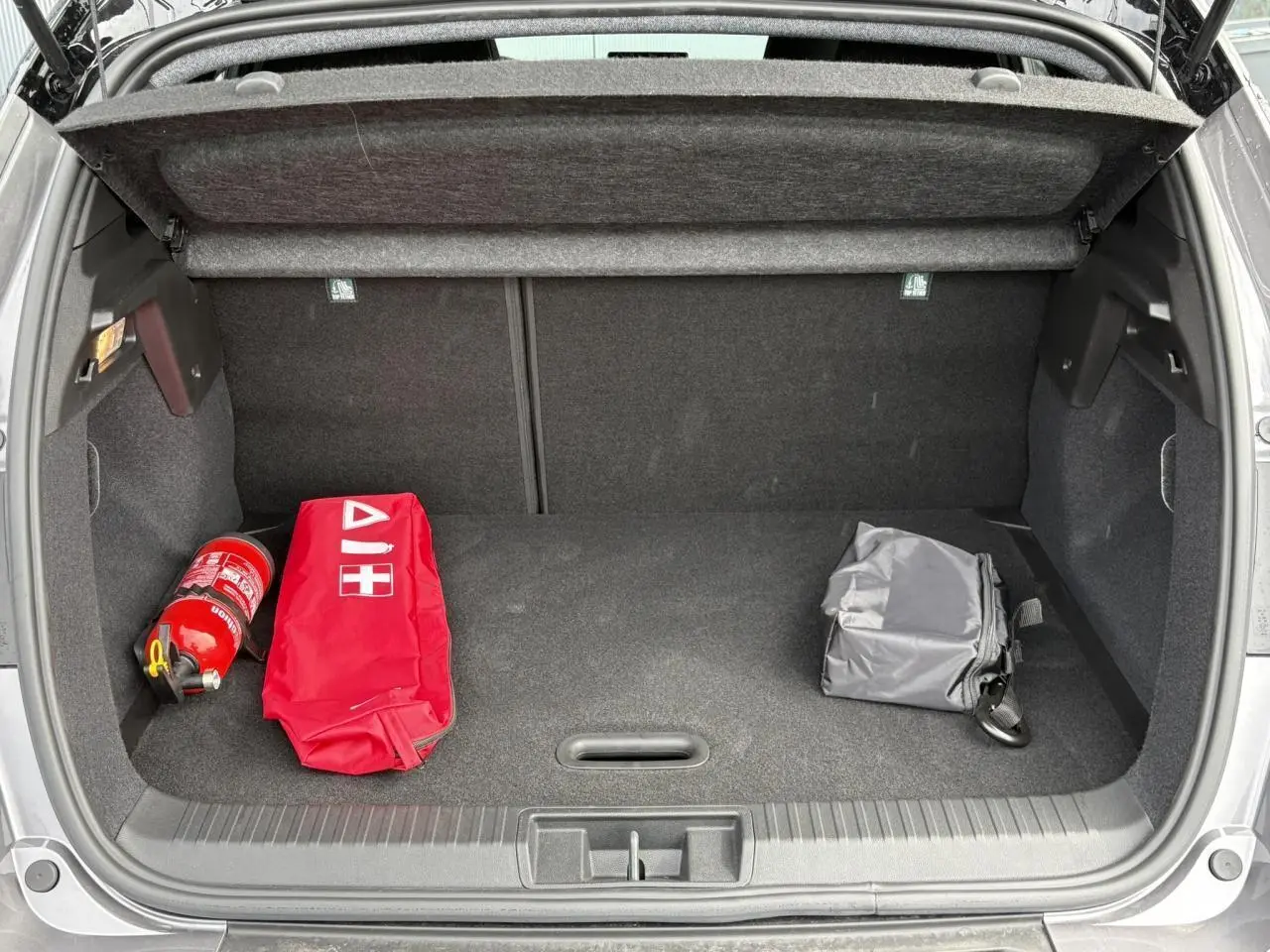 Coffre ouvert d'un Renault Captur Gris Cassiopée 2025, avec trousse de secours rouge et extincteur visibles.