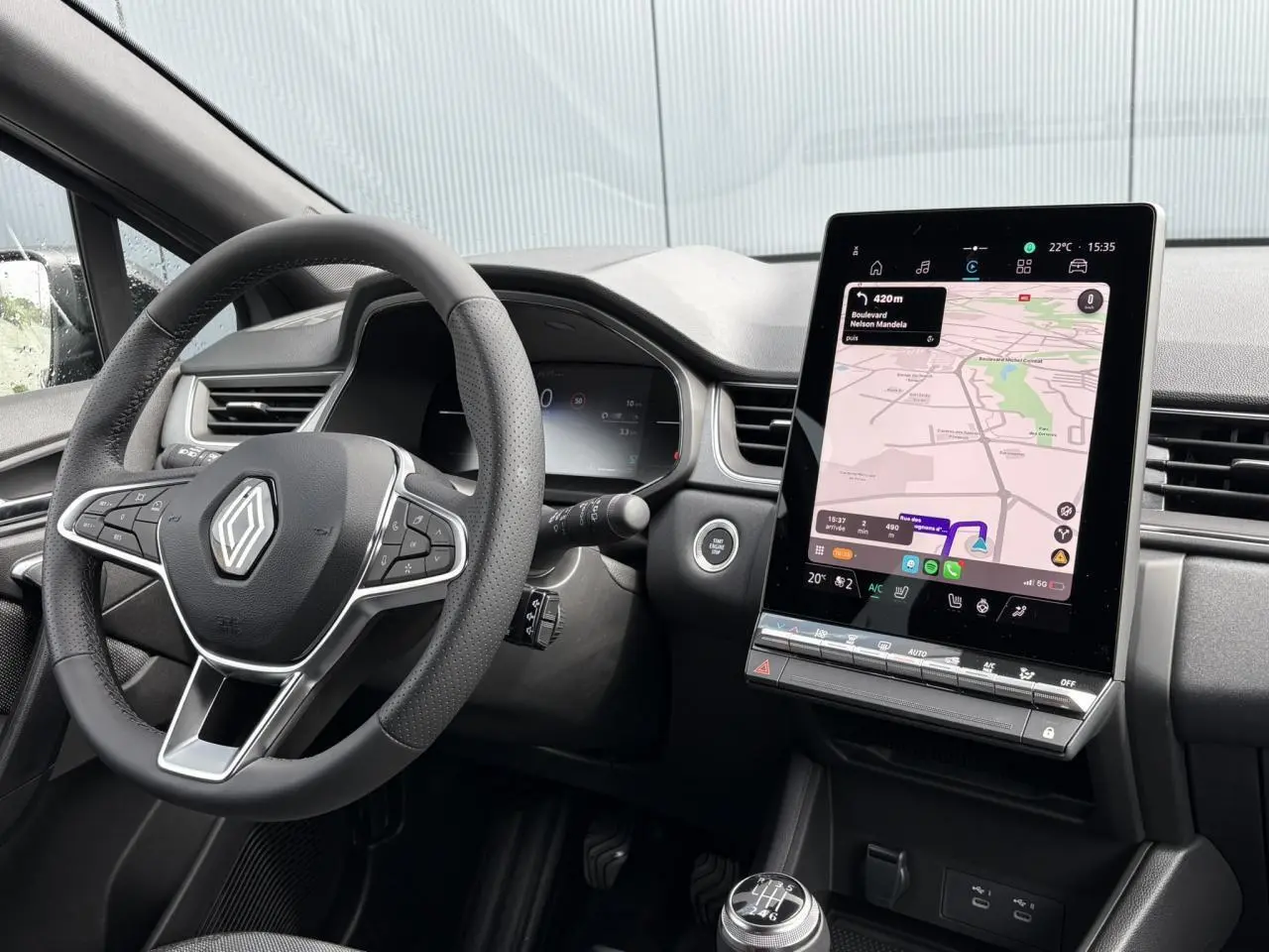 Intérieur du Renault Captur 2025 vu côté conducteur, volant multifonction et écran tactile vertical avec navigation affichée.