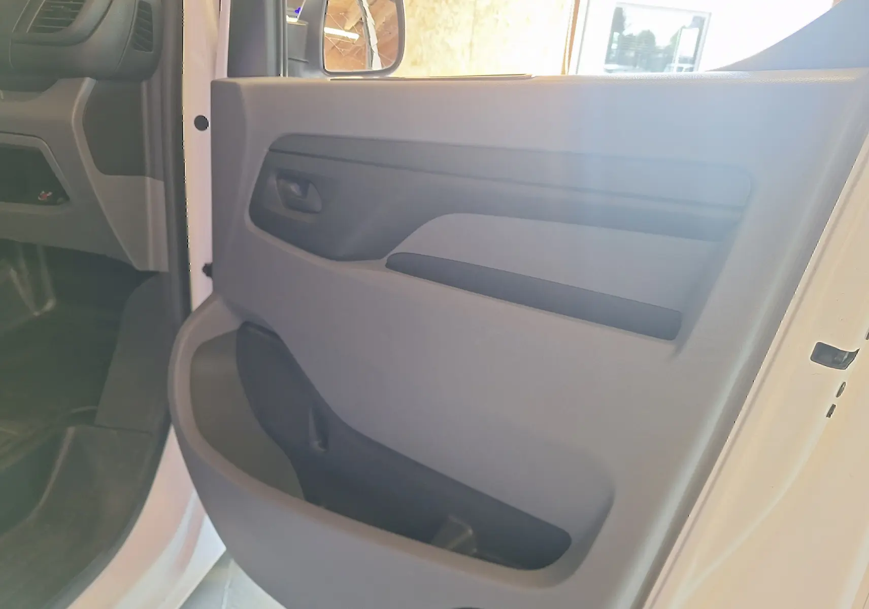 Intérieur de la porte avant gauche d'un Citroën Jumpy blanc 2020, mettant en valeur la poignée et le rangement intégré.