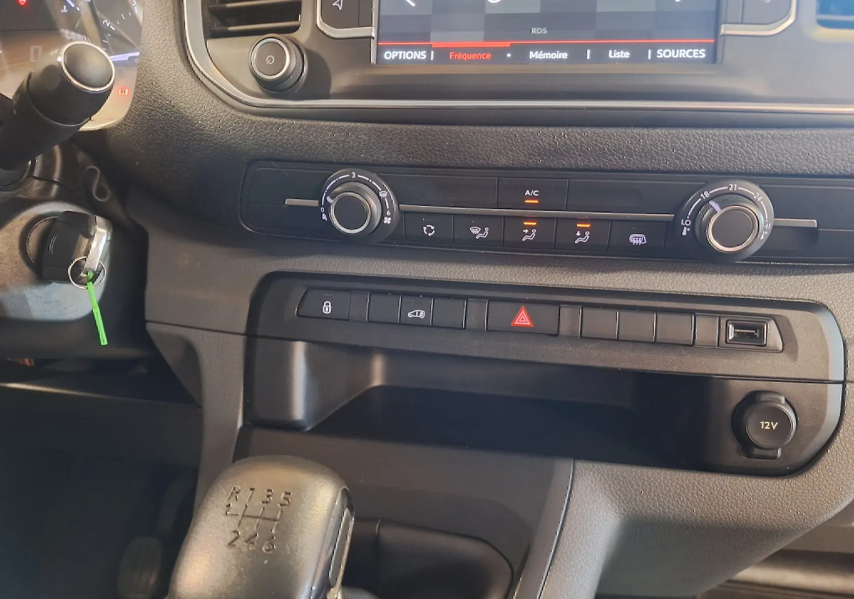 Vue rapprochée de la console centrale du Citroën Jumpy blanc 2020, avec levier de vitesses manuel et commandes climatisation.