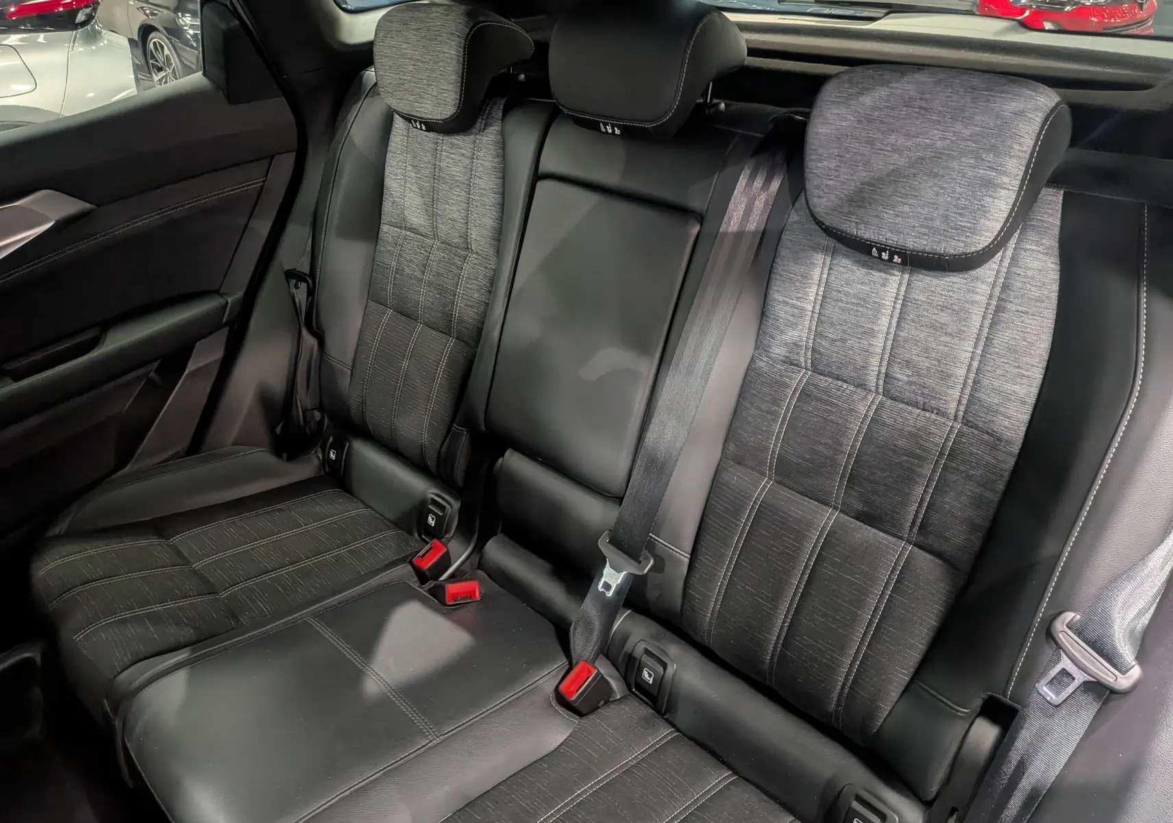 Vue rapprochée des sièges arrière en cuir noir et tissu gris du Renault Austral 2024, soulignant les ceintures de sécurité et appuie-têtes.