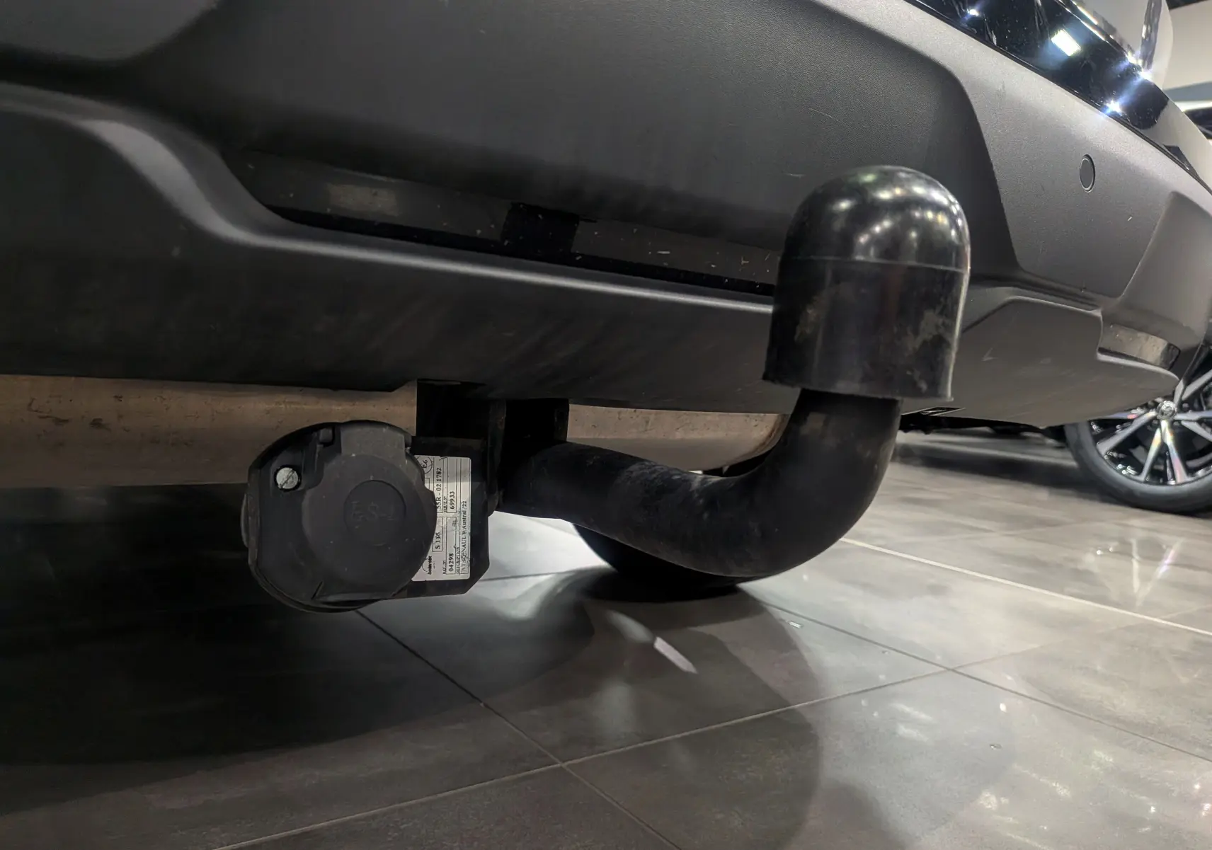 Gros plan sur l'attelage de remorque noir sous le pare-chocs arrière du Renault Austral gris Schiste avec toit noir.