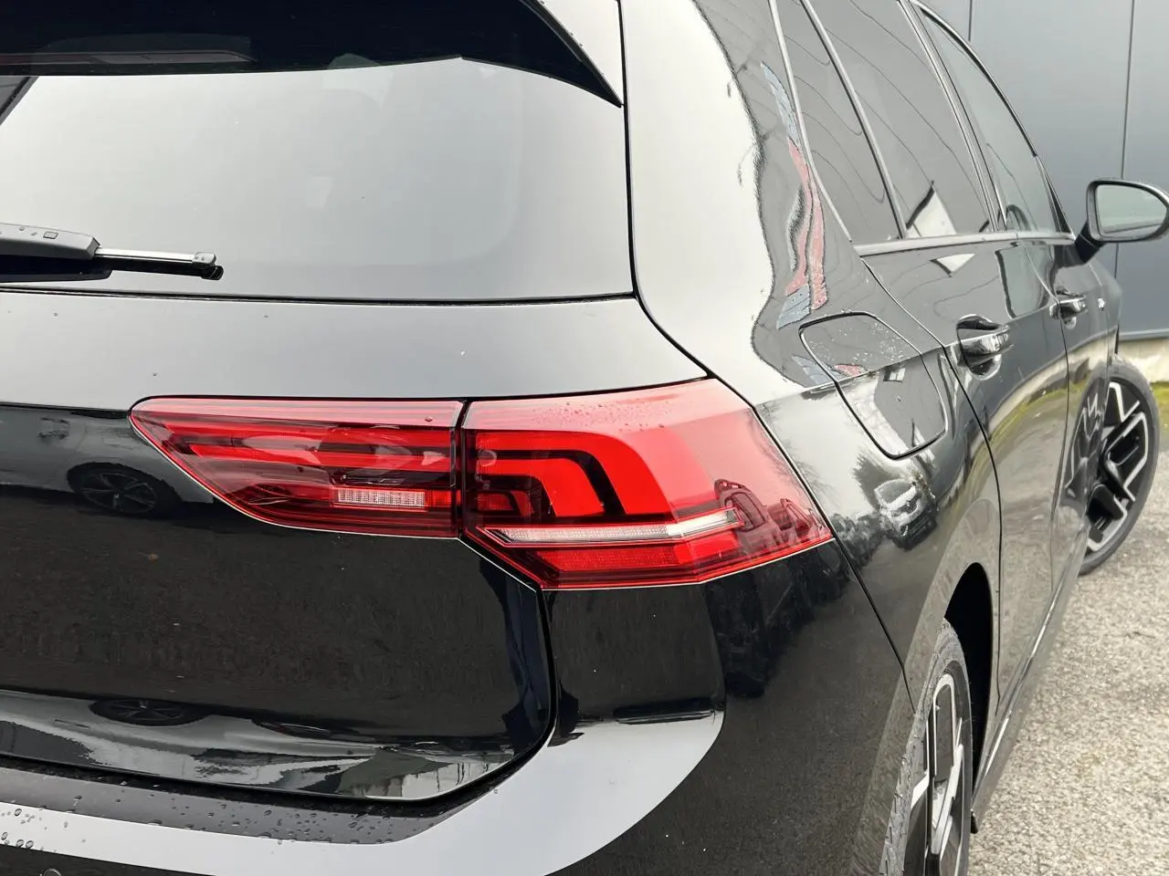 Vue arrière côté droit d'une Volkswagen Golf VIII noire avec feux arrière LED et jantes alliage 18 pouces.