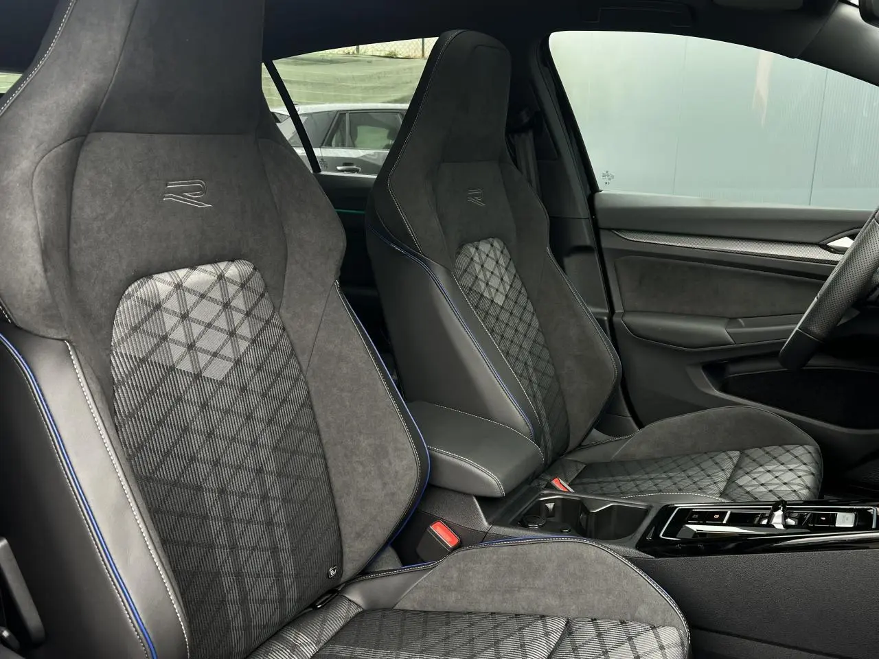 Vue intérieure des sièges avant sport R-Line en tissu et alcantara gris avec surpiqûres bleues dans une Volkswagen Golf VIII noire.