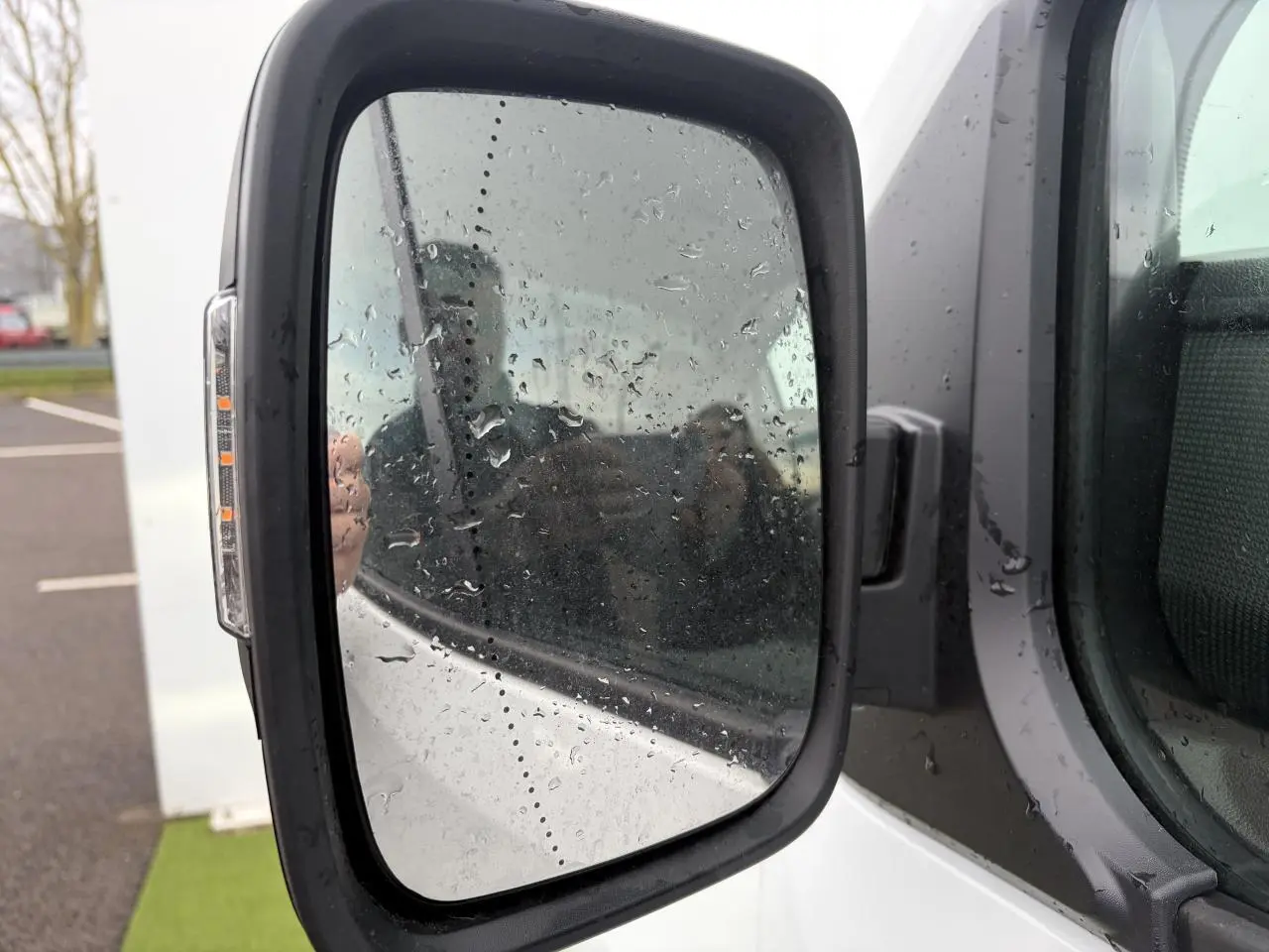 Rétroviseur gauche du Renault Trafic Fourgon blanc glacier 2025 avec clignotant intégré et traces de pluie.