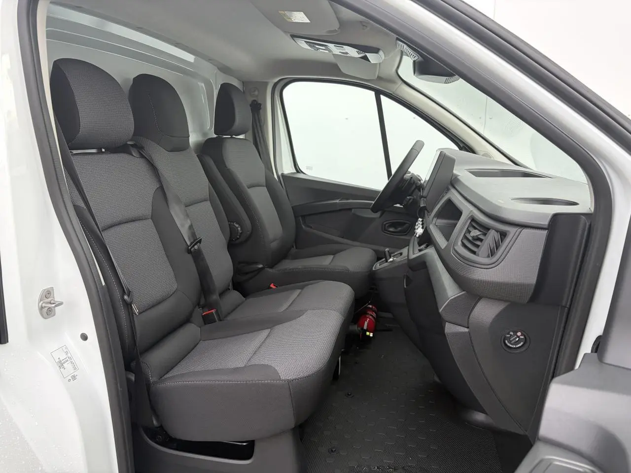 Vue intérieure côté conducteur du Renault Trafic Fourgon blanc glacier, montrant la banquette passager et le tableau de bord.