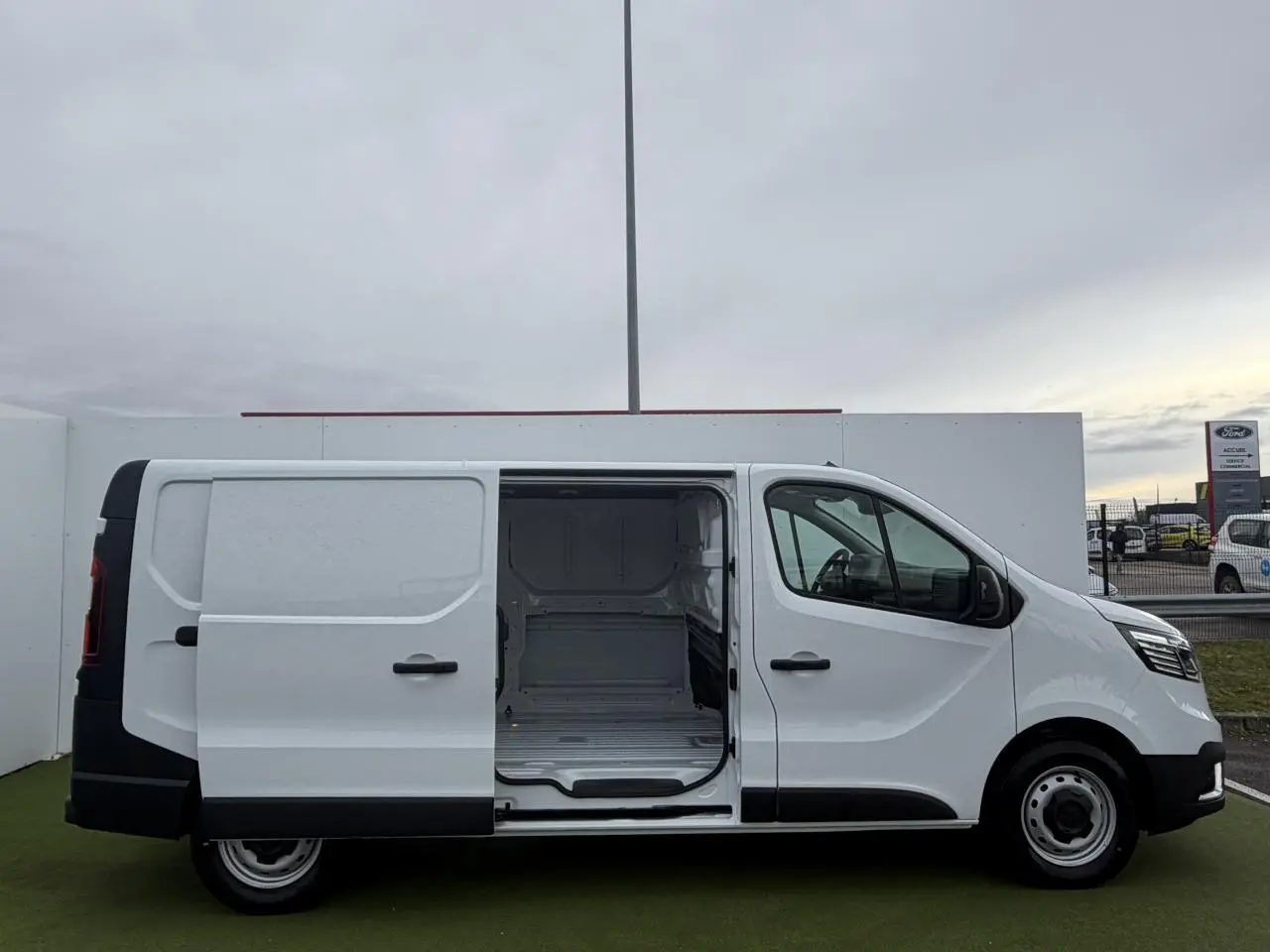 Vue latérale droite d'un Renault Trafic Fourgon blanc Glacier avec porte coulissante ouverte montrant l'espace de chargement vide.