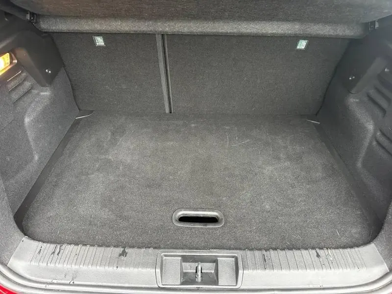 Coffre ouvert vu de face du Renault Captur 2025 Rouge Flamme/Noir Étoilé, espace de chargement vide et revêtement noir.