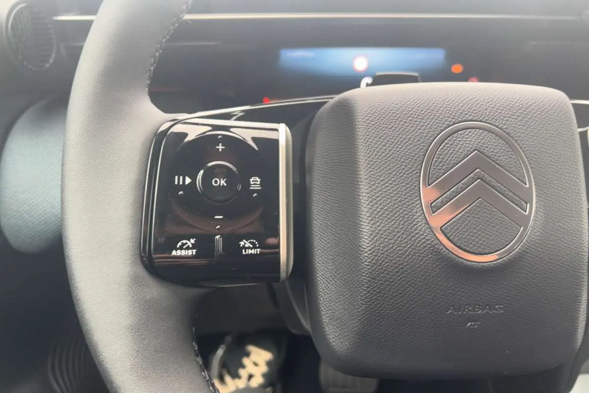 Gros plan sur le volant cuir multifonctions du Citroën C5 Aircross Hybrid 145 Plus, avec commandes d’assistance et logo central.
