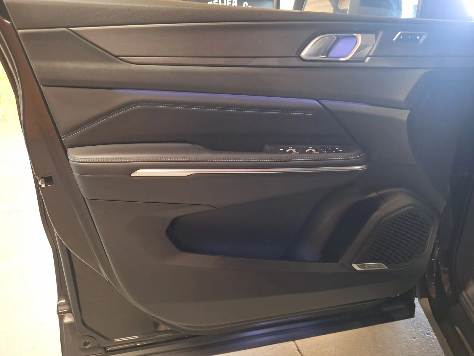 Vue rapprochée de la porte avant gauche noire du LYNK & CO 01 2023 avec commandes de vitres et haut-parleur intégré.