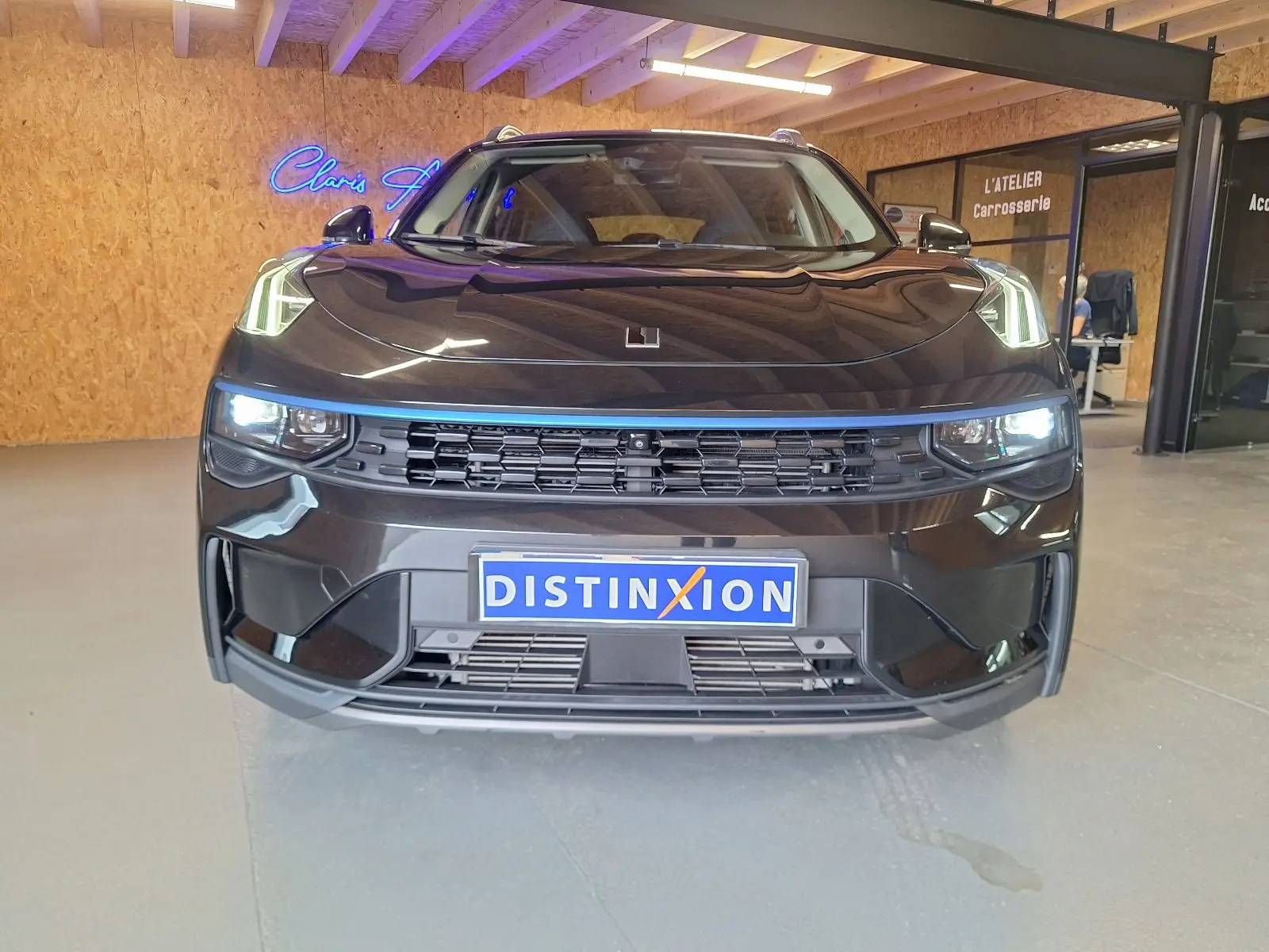 Vue frontale d'un SUV LYNK & CO 01 noir avec phares allumés et calandre noire dans un garage.