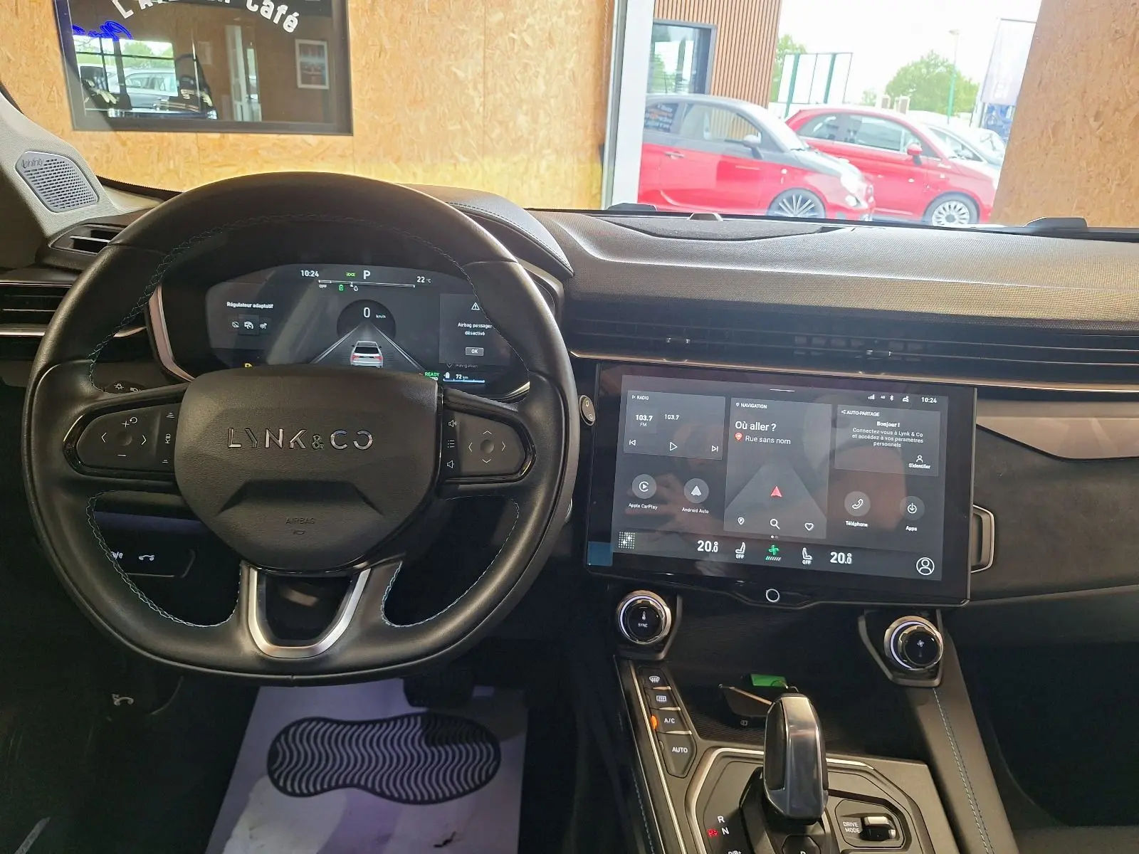 Vue intérieure du tableau de bord et volant noir du Lynk & Co 01 hybride rechargeable 2023 avec écran tactile central allumé.