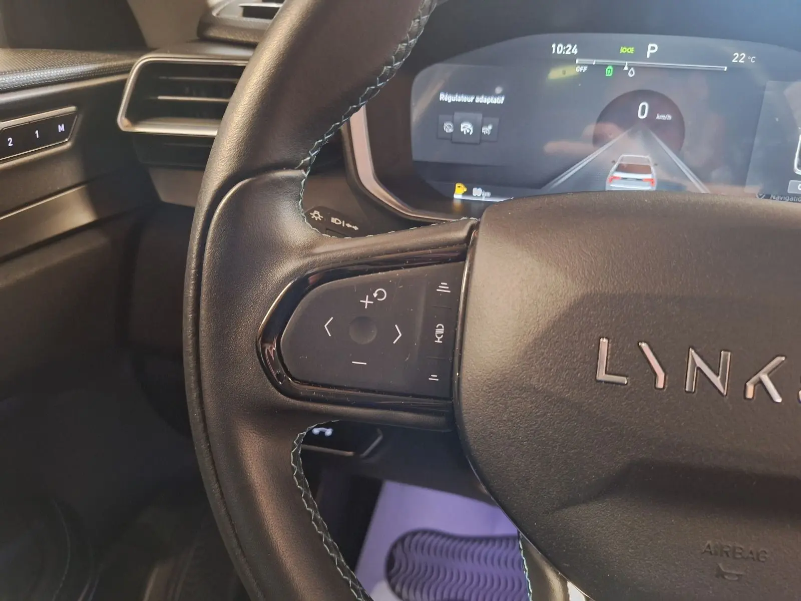 Gros plan sur le volant noir du LYNK & CO 01 2023 avec commandes intégrées et affichage numérique du régulateur adaptatif.