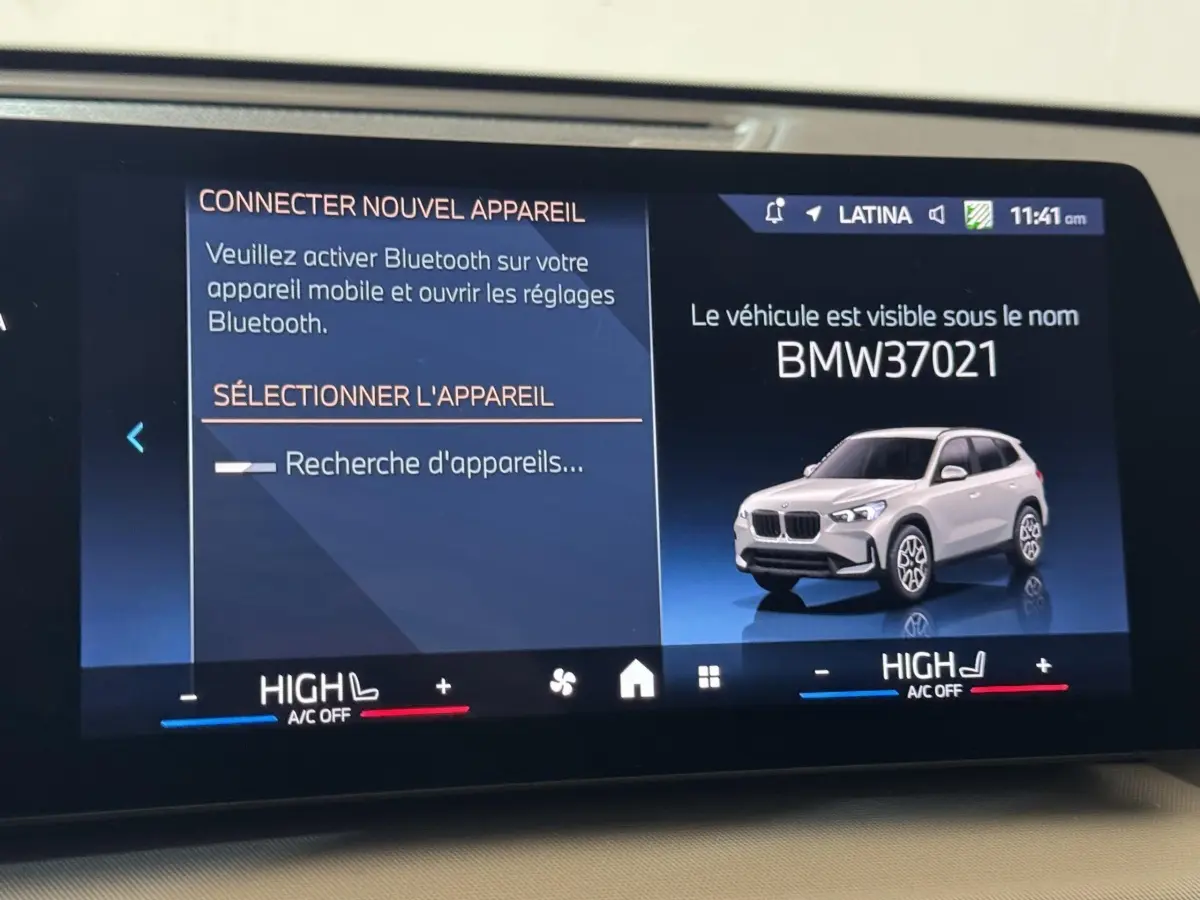 Affichage digital intérieur montrant une BMW X1 gris clair en 3/4 avant sur écran tactile du tableau de bord.