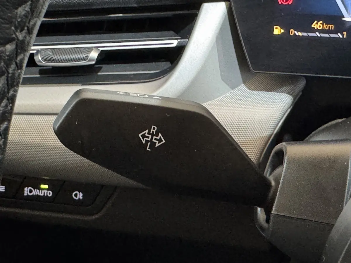 Gros plan sur la commande de réglage des rétroviseurs à gauche du volant dans l’habitacle gris clair du BMW X1 2024.