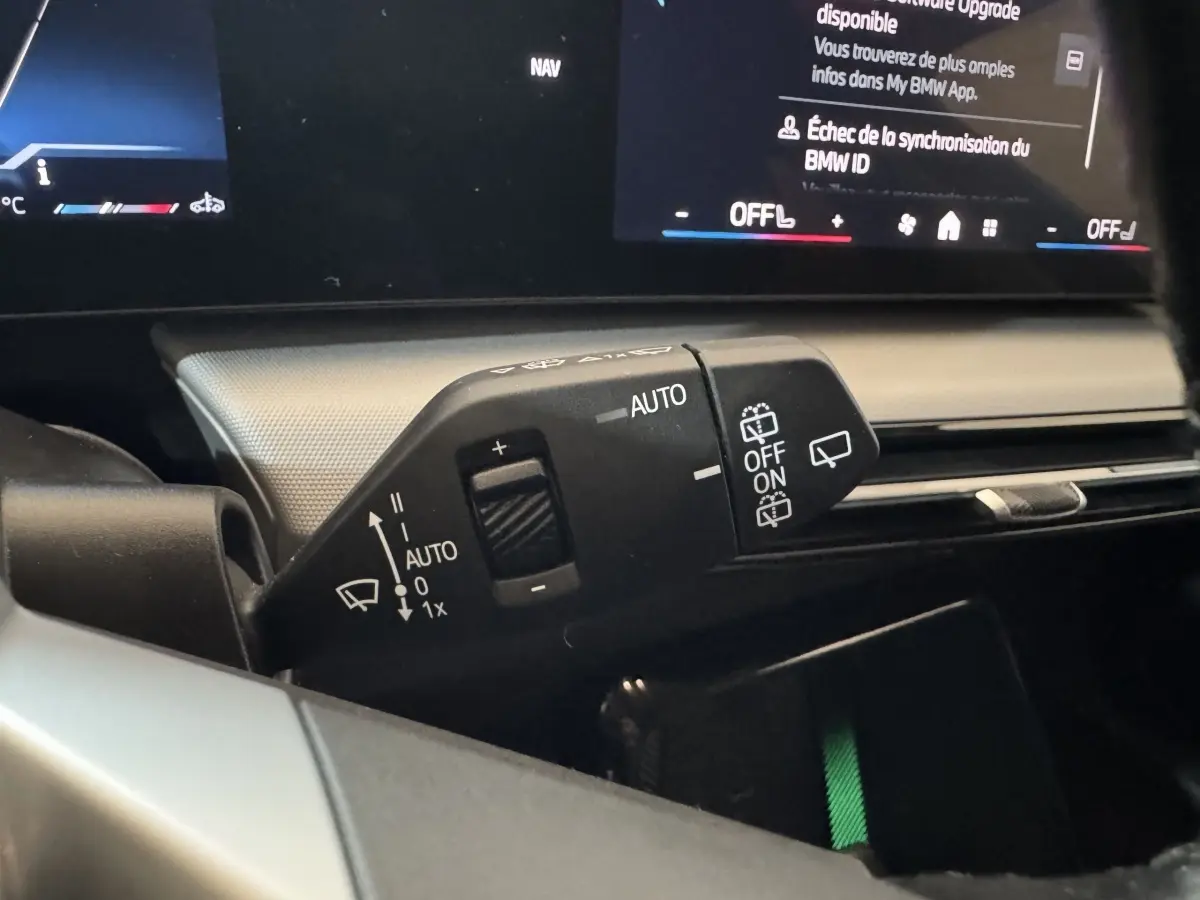 Gros plan sur la commande d’essuie-glace à gauche du volant du BMW X1 gris foncé 2024 avec affichage digital en arrière-plan.