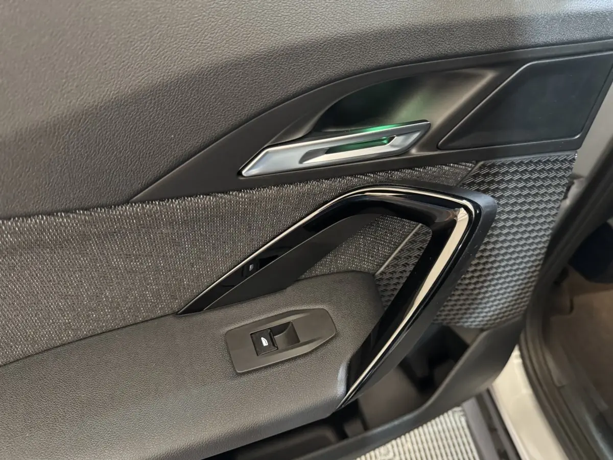 Détail de la porte intérieure côté conducteur du BMW X1 2024, avec garniture noire texturée et poignée argentée.