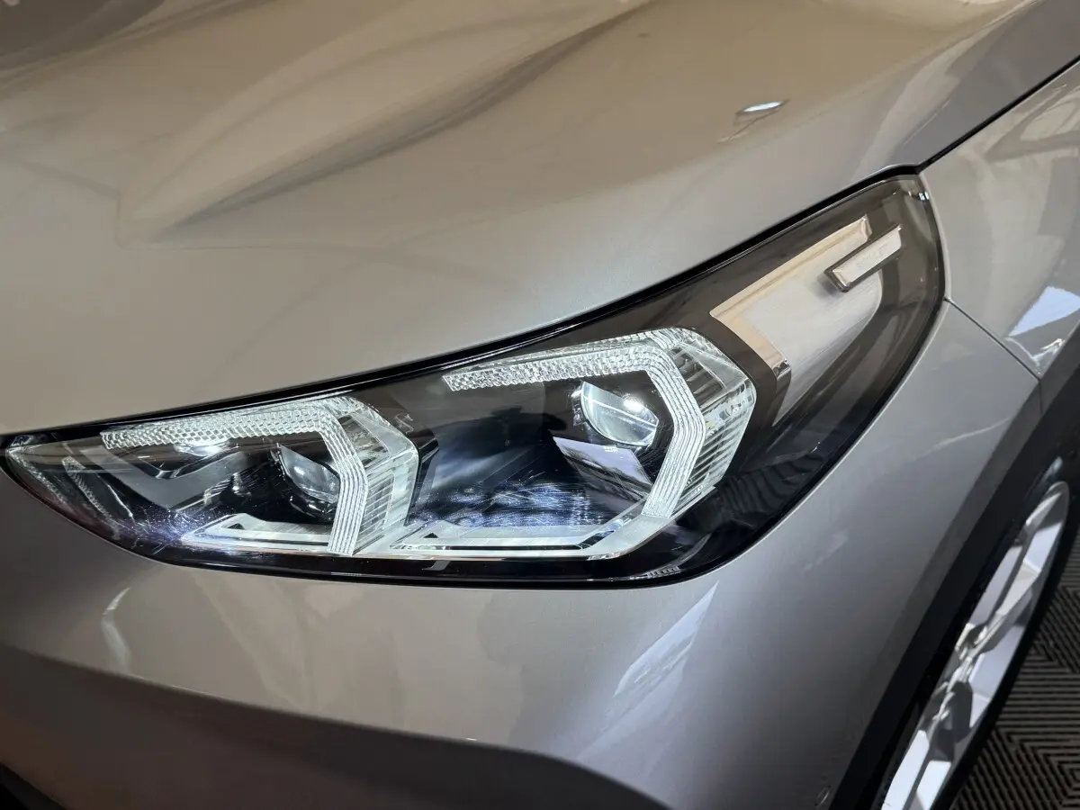 Gros plan sur le phare avant droit LED du BMW X1 sDrive20i gris foncé, soulignant ses lignes modernes et précises.