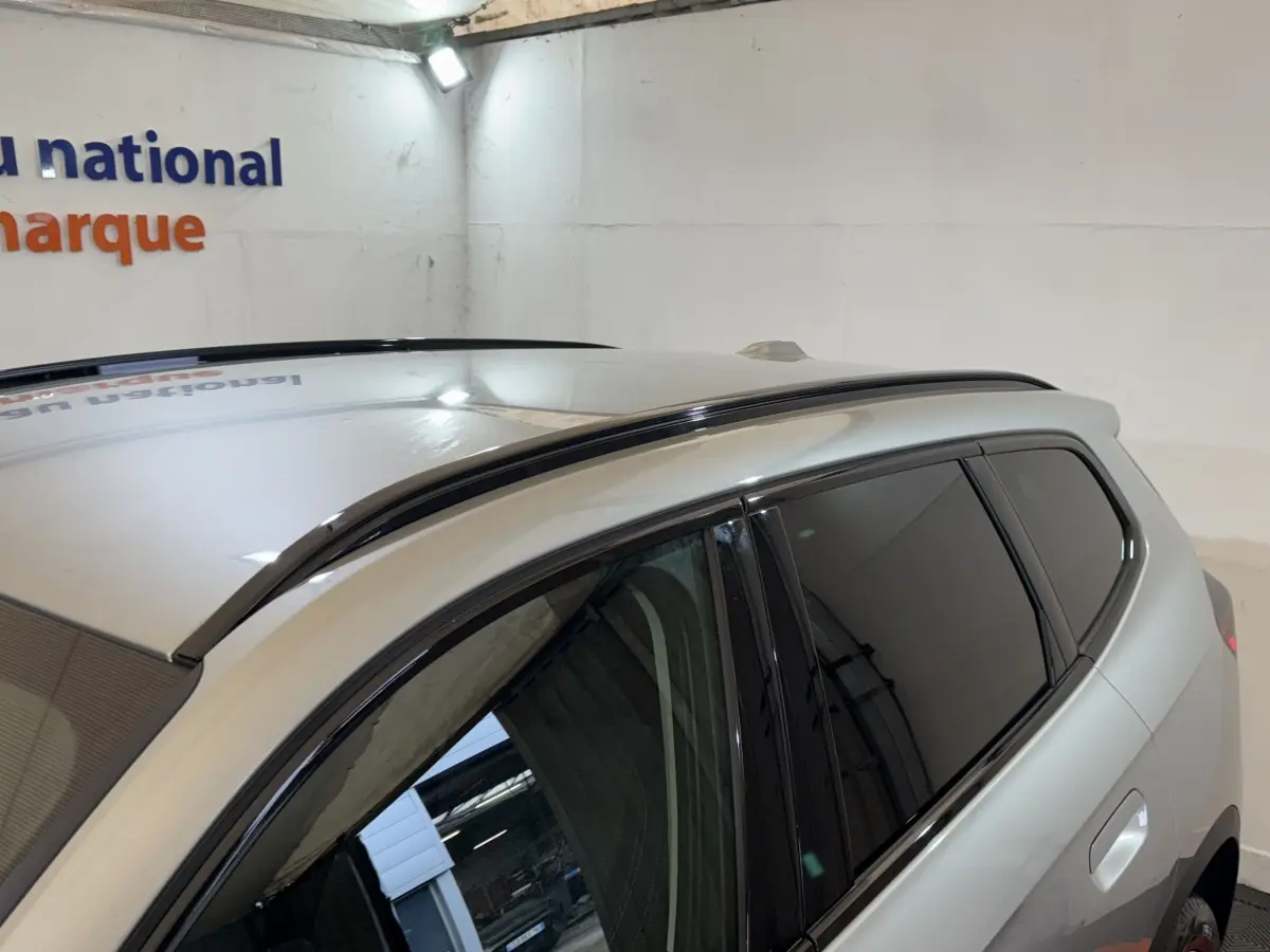 Vue rapprochée du toit et des vitres teintées côté droit du BMW X1 gris foncé en intérieur.