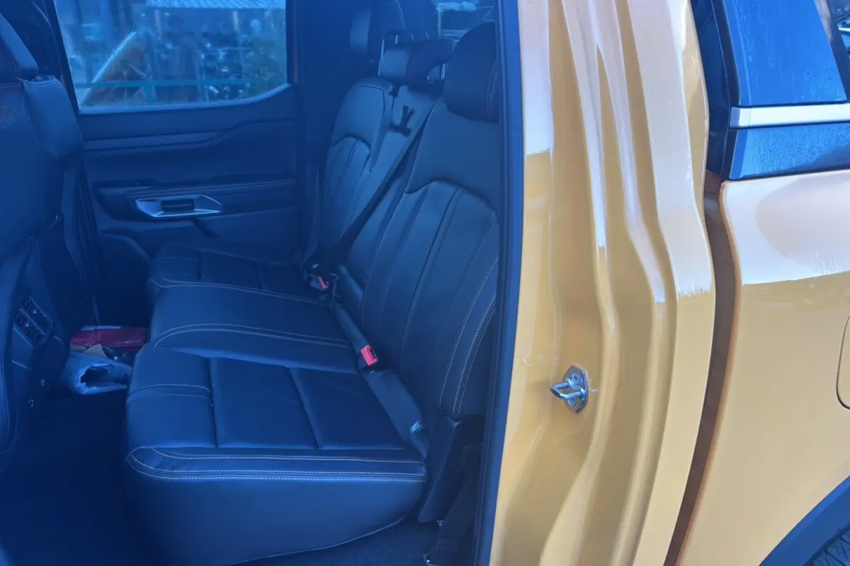 Vue intérieure arrière côté droit du Ford Ranger Cyber orange, montrant les sièges en cuir noir avec surpiqûres contrastantes.