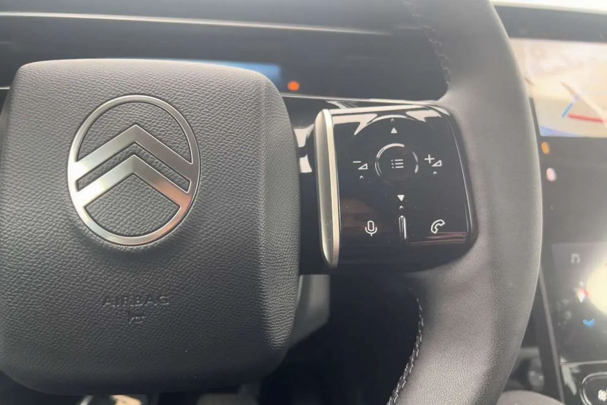 Gros plan sur le volant cuir multifonctions de la Citroën C5 Aircross Hybrid 2026 avec logo chrome au centre.