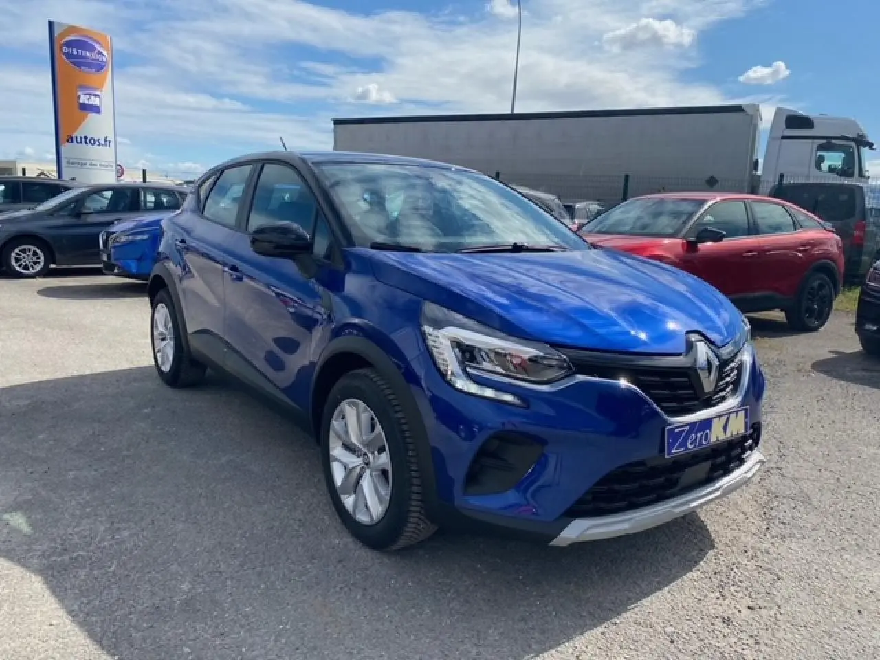 Renault Captur Evolution Mild Hybrid 140 EDC bleu Iron vu en 3/4 avant sur parking extérieur avec plaque Zero KM.