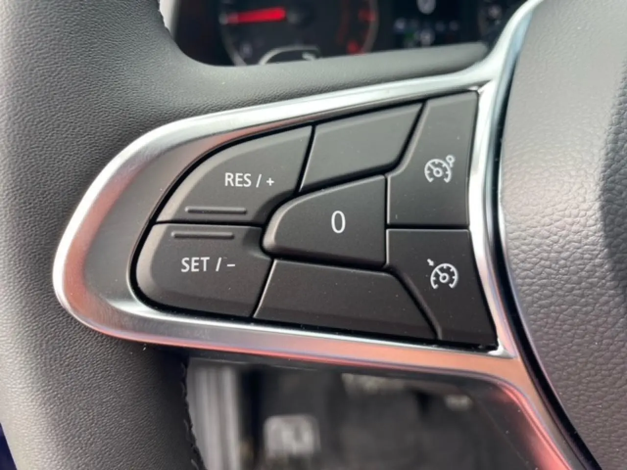 Gros plan sur les commandes du régulateur de vitesse au volant du Renault Captur bleu Evolution Mild Hybrid 2023.