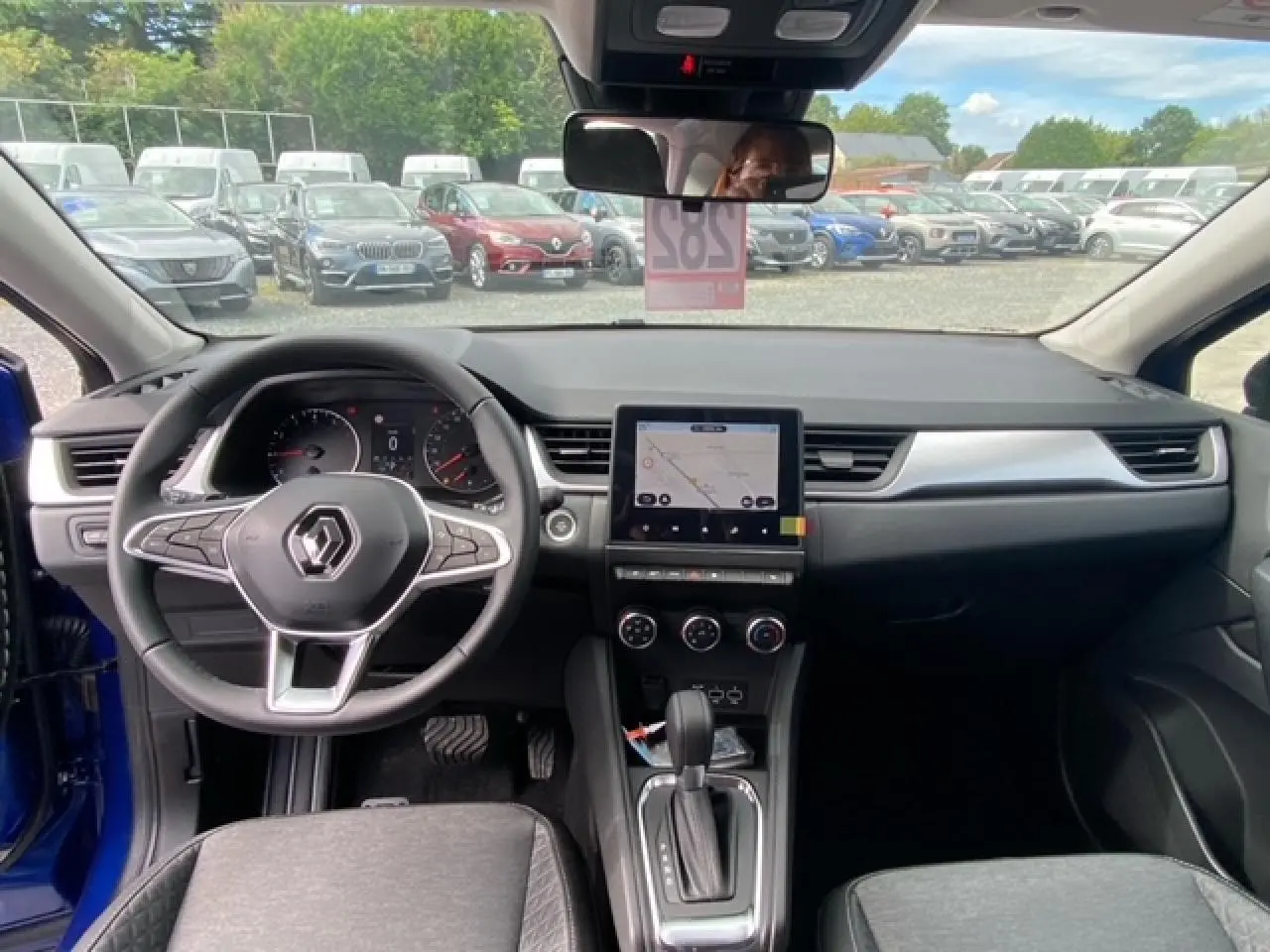 Vue intérieure du tableau de bord du Renault Captur bleu 2023 avec écran tactile 9,3 pouces et volant multifonction.