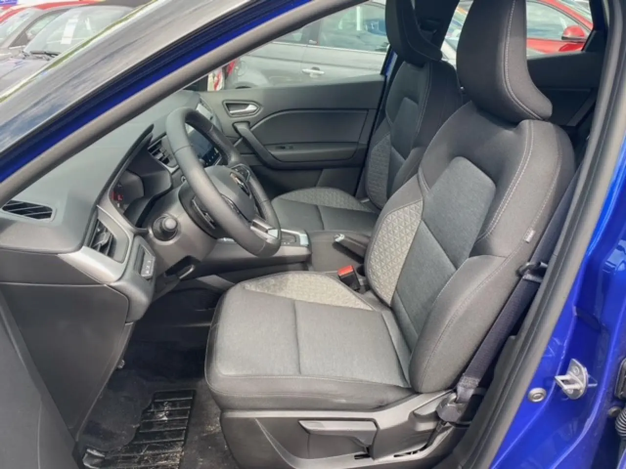 Intérieur côté conducteur du Renault Captur bleu 2023, montrant sièges tissu gris et tableau de bord moderne.