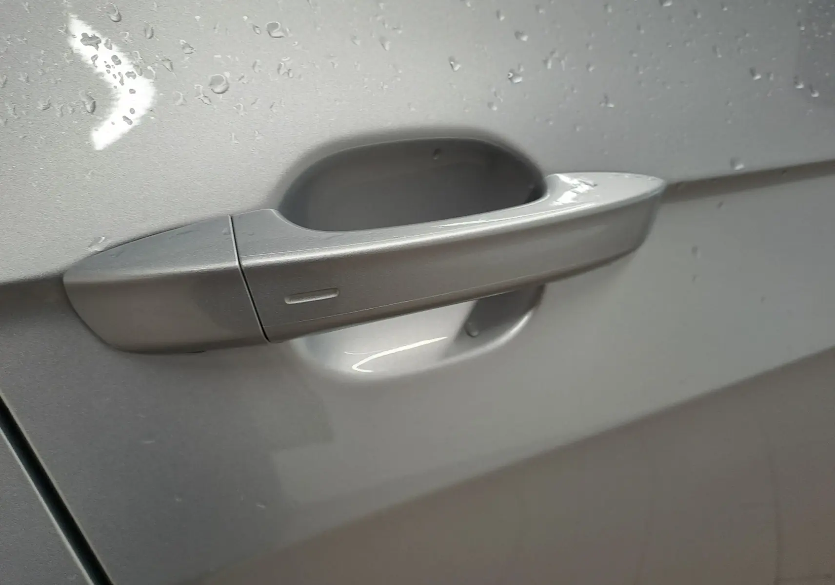 Poignée de porte côté gauche du Volkswagen T-Cross 2025 R-Line Edition en Reflet d'argent avec gouttes d'eau visibles.