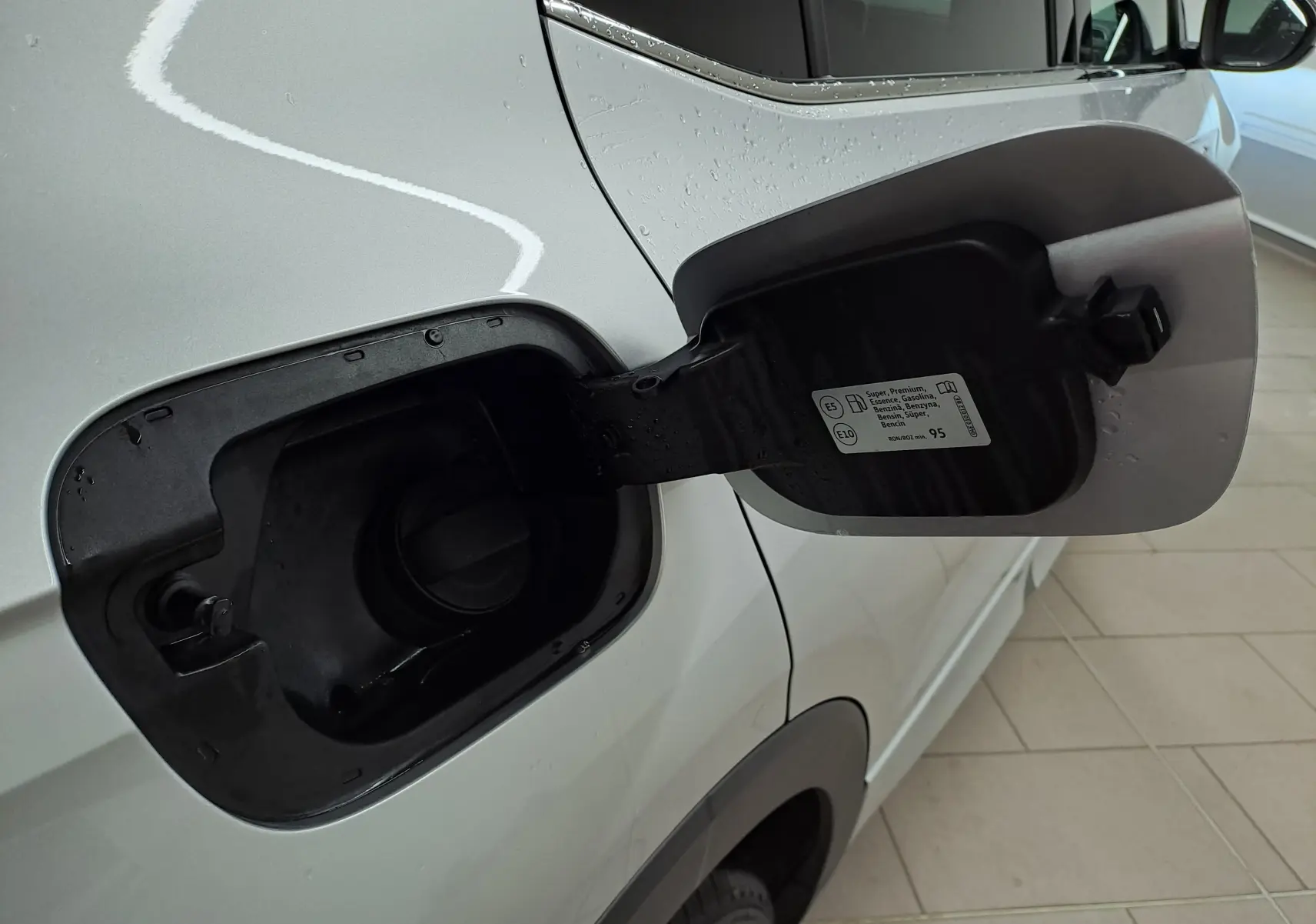 Détail de la trappe à carburant ouverte côté gauche d'un Volkswagen T-Cross 2025 Reflet d'argent, version essence.