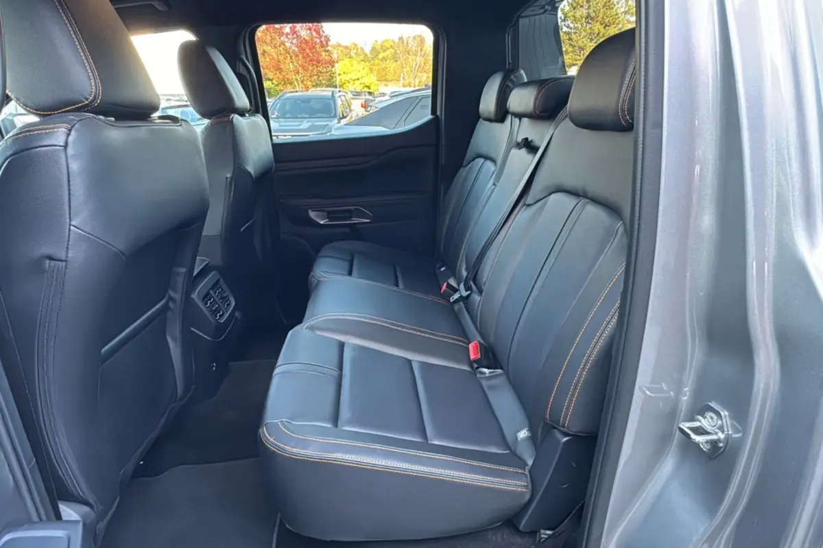 Vue intérieure arrière côté droit du Ford Ranger 2.3 PHEV gris iconic, sièges en cuir noir avec surpiqûres orange.