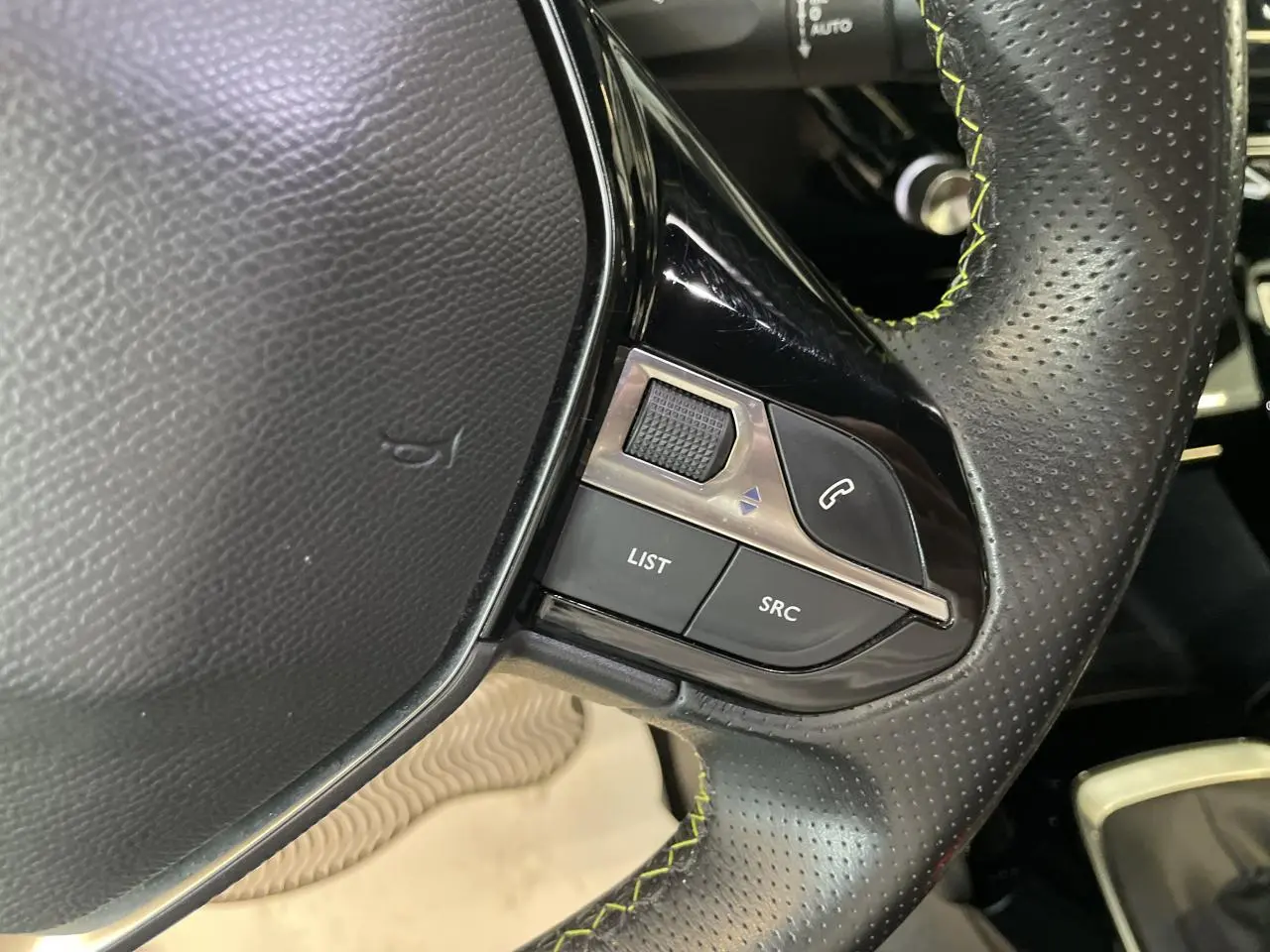 Gros plan sur le volant cuir perforé noir avec surpiqûres vertes et commandes multimédia du Peugeot 2008 GT Line 2019.
