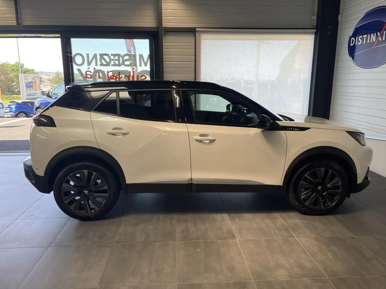 Peugeot 2008 blanc avec toit noir en vue profil côté gauche, jantes noires et détails GT Line visibles.
