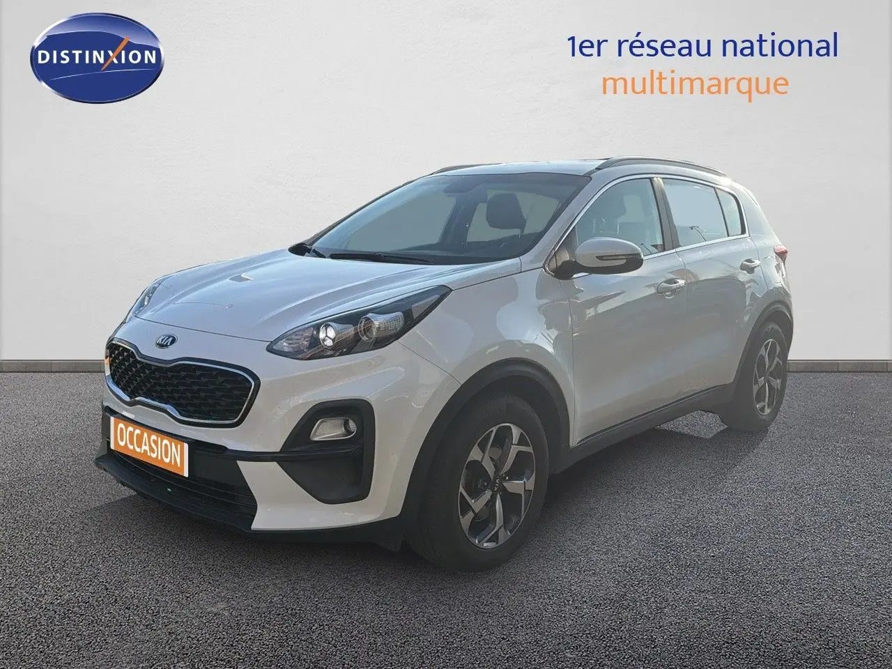 KIA Sportage blanc nacré métal en 3/4 avant droit, avec calandre noire et jantes bi-ton visibles.